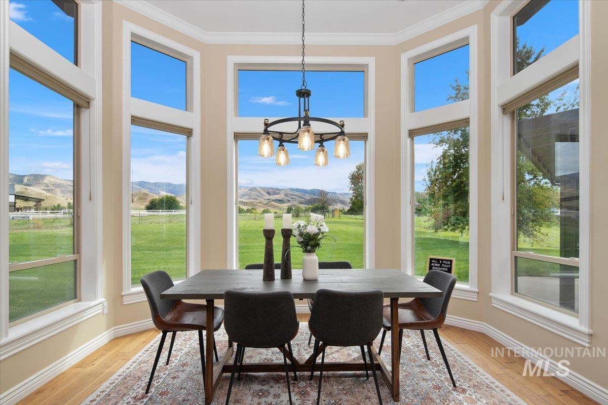 Dinning room featuring a mountain view, ornamental molding, wood finished floors, and a chandelier.