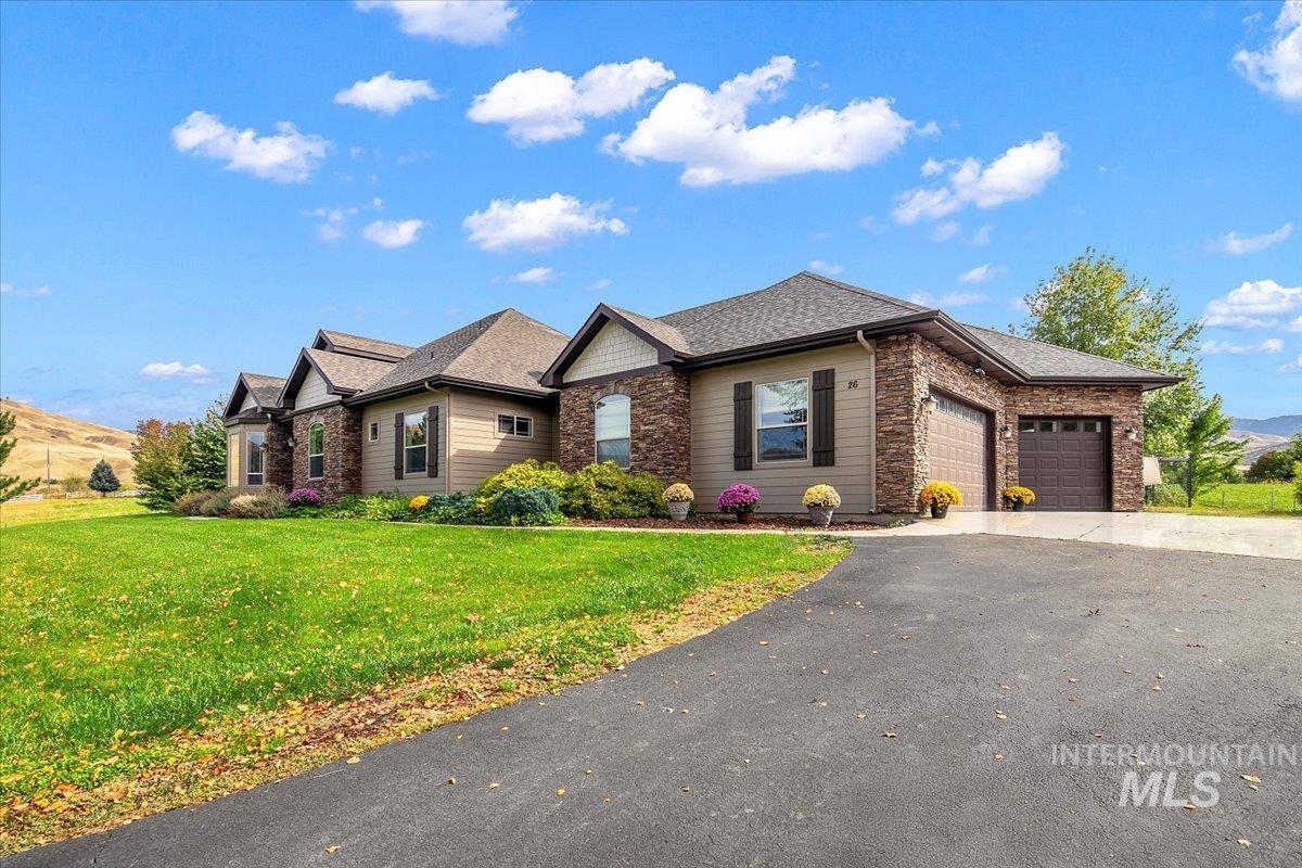 View of front of home with an attached garage, asphalt driveway, a front yard, and roof with shingles