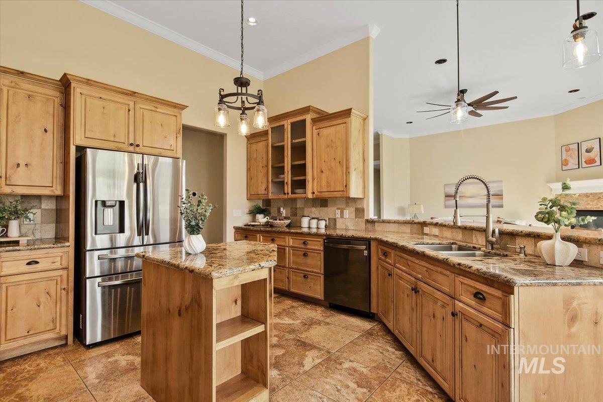 Kitchen featuring updated hanging light fixtures, glass insert cabinets, new appliances include stainless steel fridge,  oven, gas cooktop, microwave and refigerator. Kitchen features a decorative backsplash, and light stone counters.