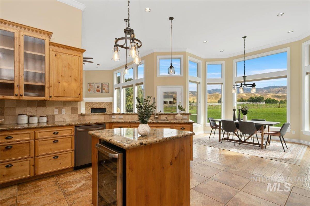 Kitchen with ornamental molding, light stone counters, a chandelier, hanging light fixtures, and beverage cooler. Glass insert cabinets, all new appliances include stainless steel fridge, oven, gas cooktop, microwave, and refigerator.