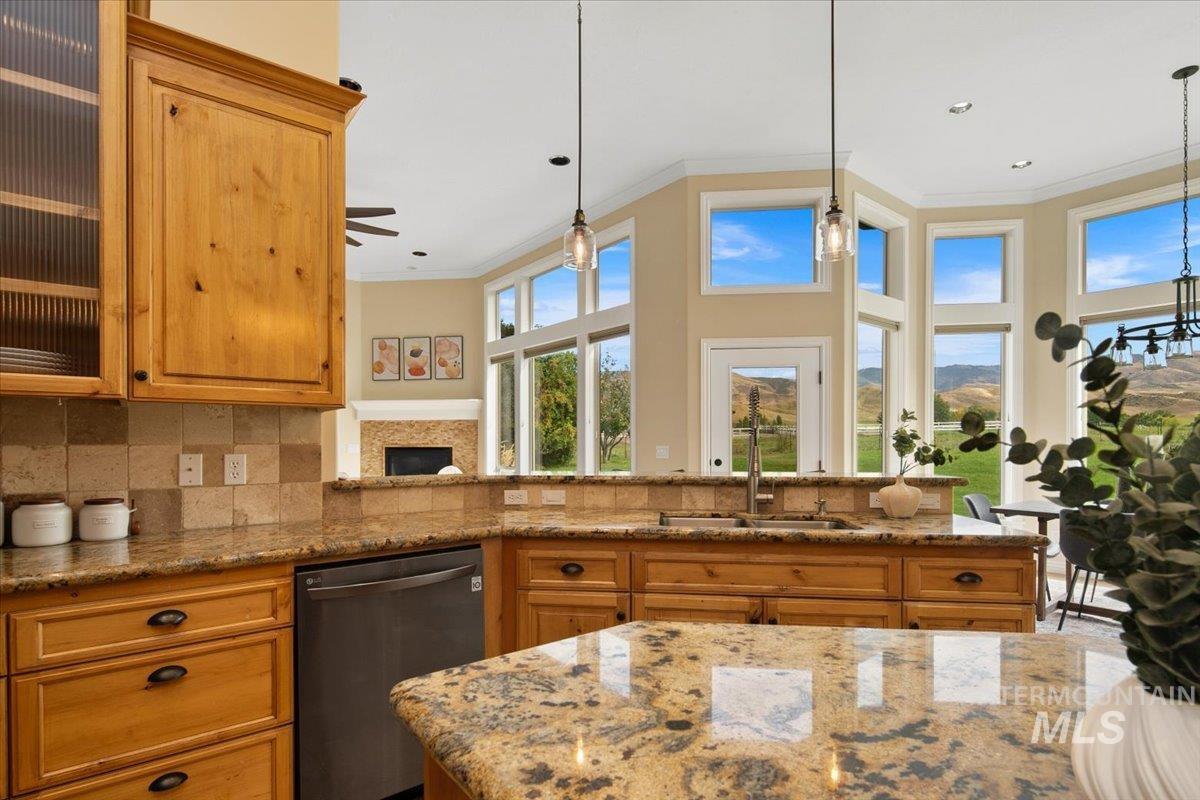 Kitchen with crown molding, stainless steel dishwasher, cabinetry, backsplash, and light stone counters.