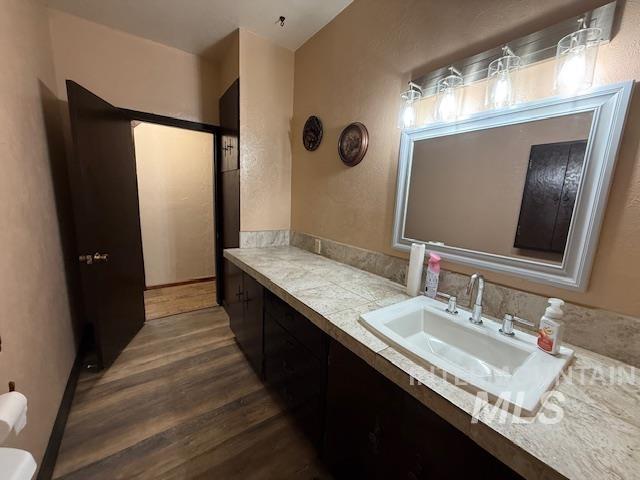 Bathroom featuring vanity, dark wood finished floors, and a textured wall
