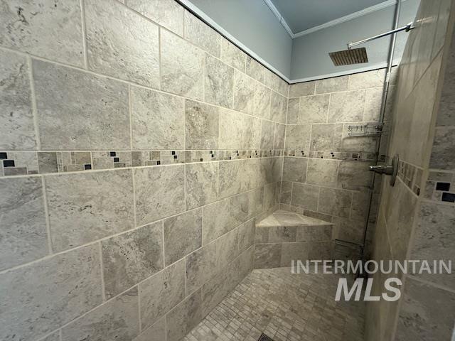 Bathroom with tiled shower and crown molding