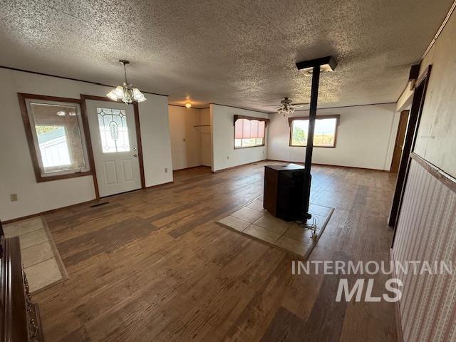 Entryway featuring a wood stove, a ceiling fan, dark wood-style floors, and a textured ceiling