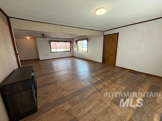 Unfurnished room with dark wood finished floors, crown molding, and ceiling fan
