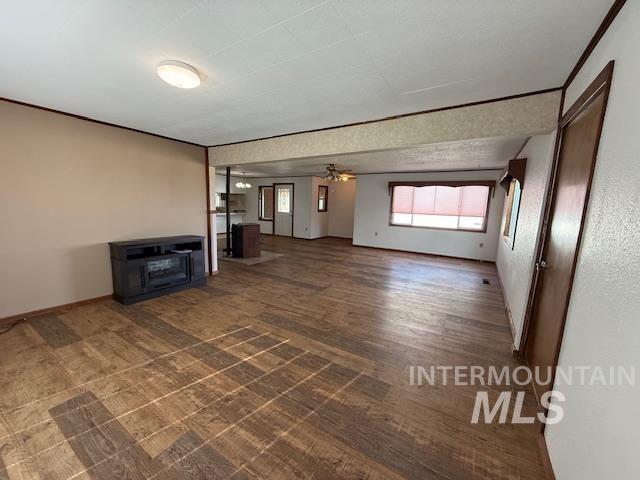 Unfurnished living room featuring ceiling fan and dark wood-style flooring