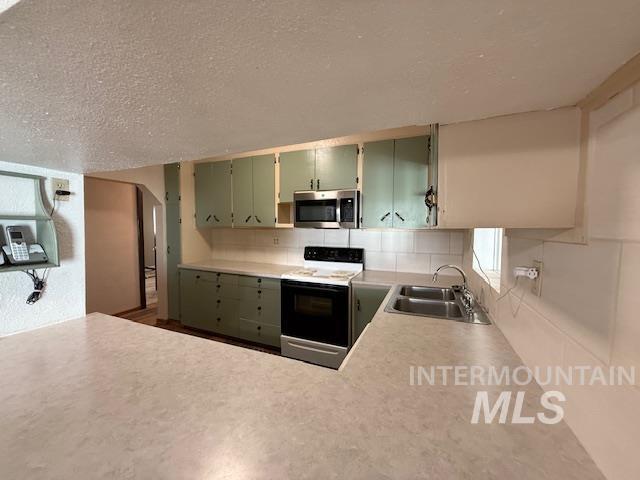 Kitchen featuring green cabinets, electric range, light countertops, a textured ceiling, and decorative backsplash