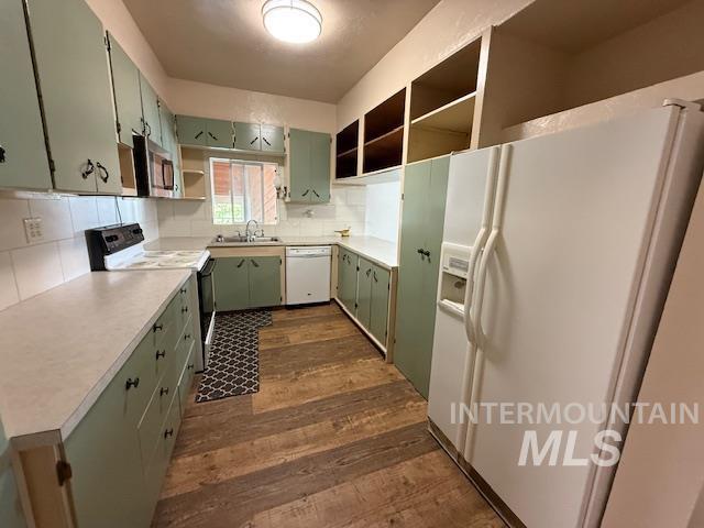Kitchen featuring green cabinets, white appliances, light countertops, dark wood-type flooring, and open shelves