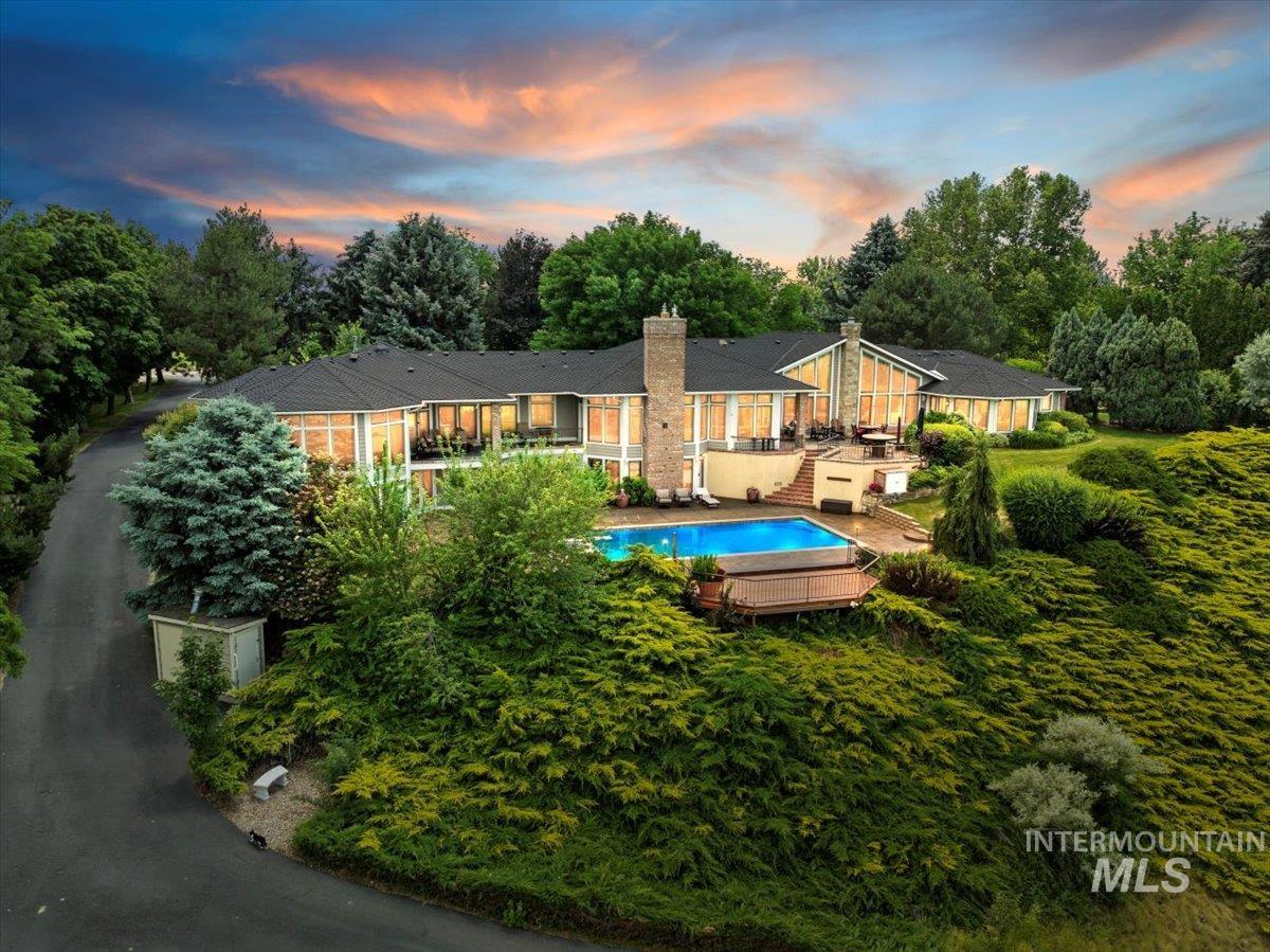 Rear view of property featuring a chimney, an outdoor pool, and view of scattered trees