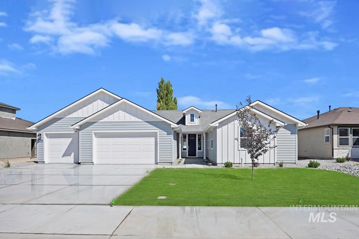 View of front of house with board and batten siding, driveway, a front lawn, and a garage