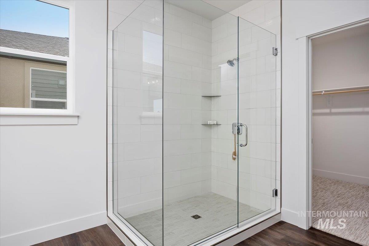 Full bath featuring a stall shower, dark wood finished floors, and a walk in closet