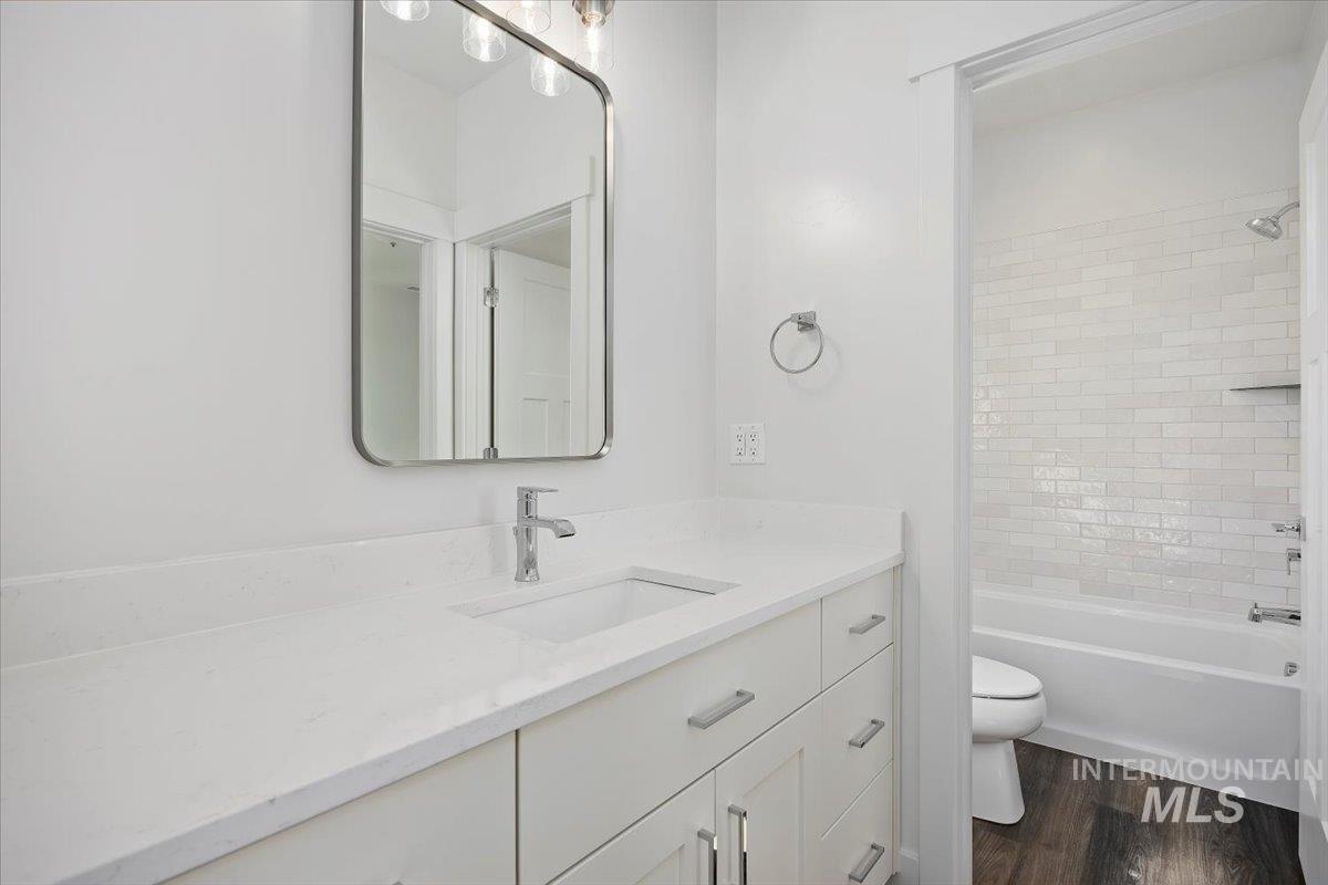 Bathroom with tub / shower combination, vanity, and dark wood finished floors