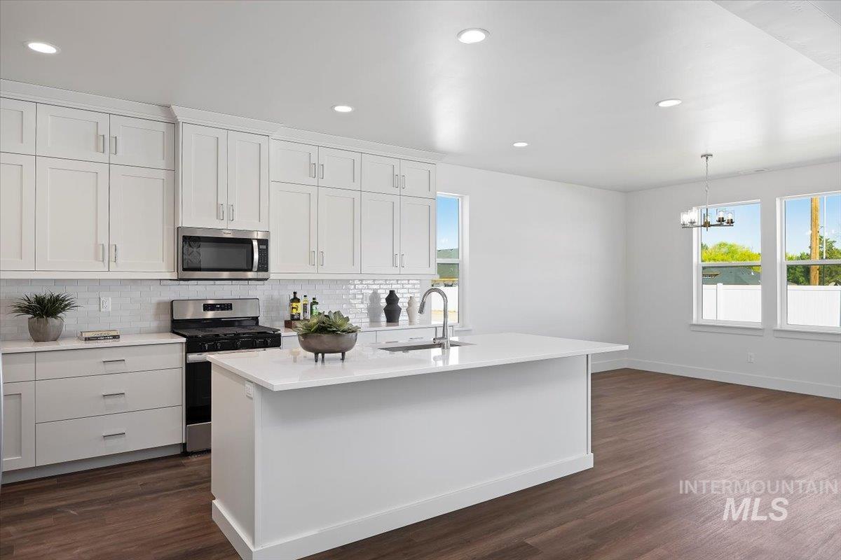 Kitchen featuring stainless steel appliances, tasteful backsplash, recessed lighting, dark wood-style flooring, and hanging light fixtures