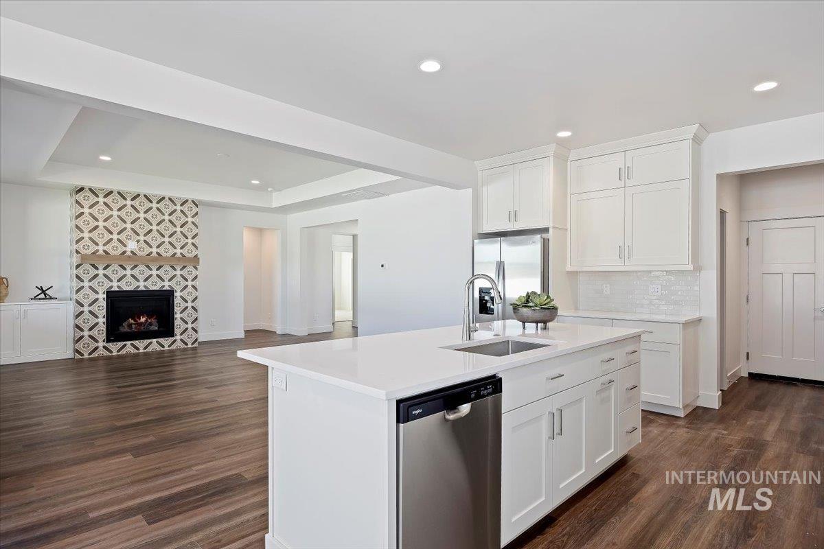 Kitchen with open floor plan, white cabinets, appliances with stainless steel finishes, recessed lighting, and dark wood finished floors