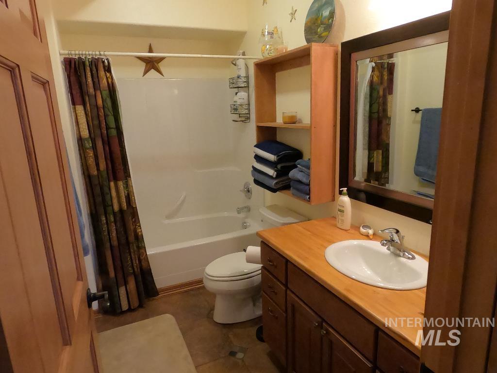 Full bath featuring vanity, shower / tub combo with curtain, and tile patterned floors