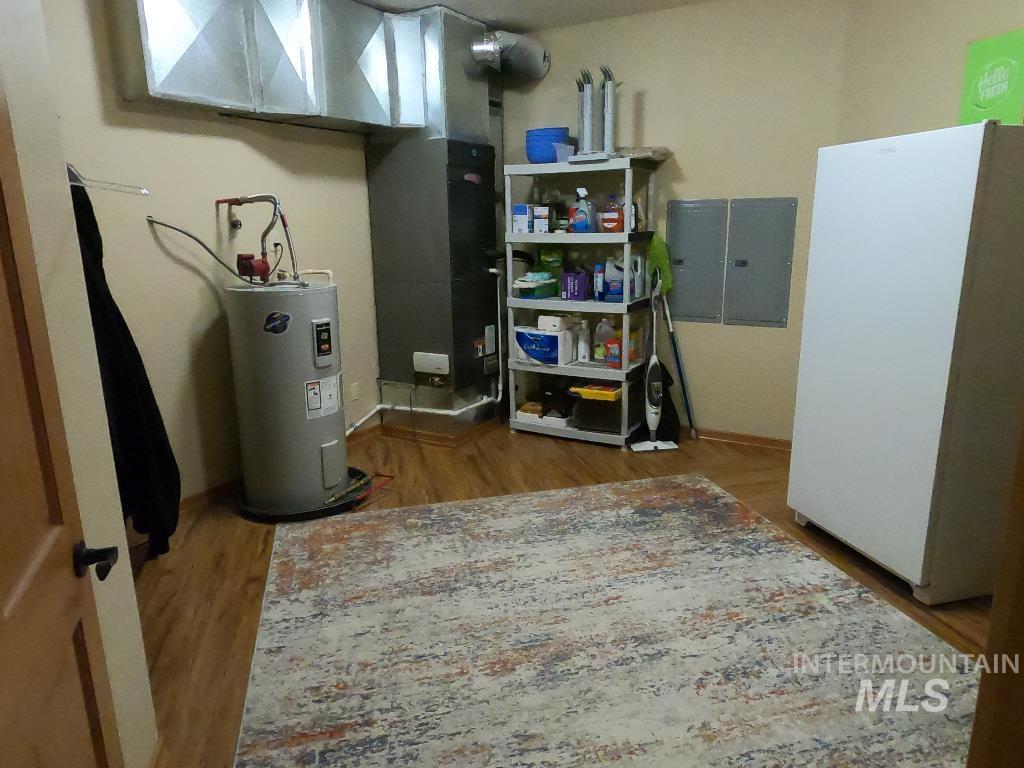 Utilities featuring electric water heater, electric panel, and heating unit