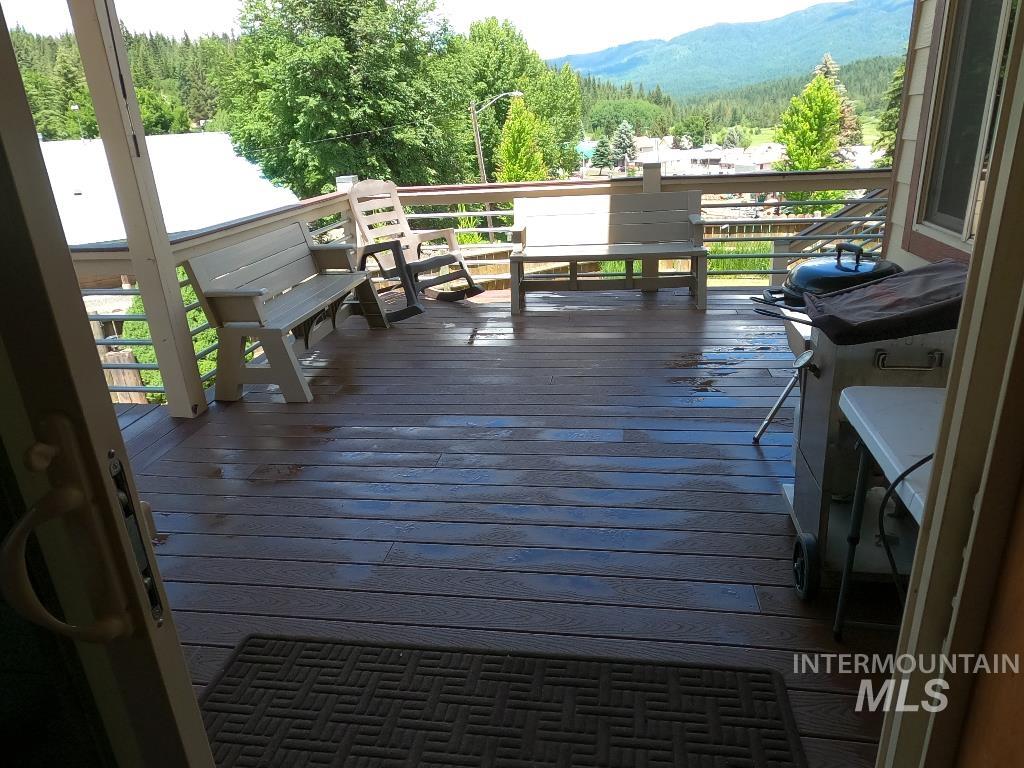 Wooden deck with a mountain view, area for grilling, and a forest view