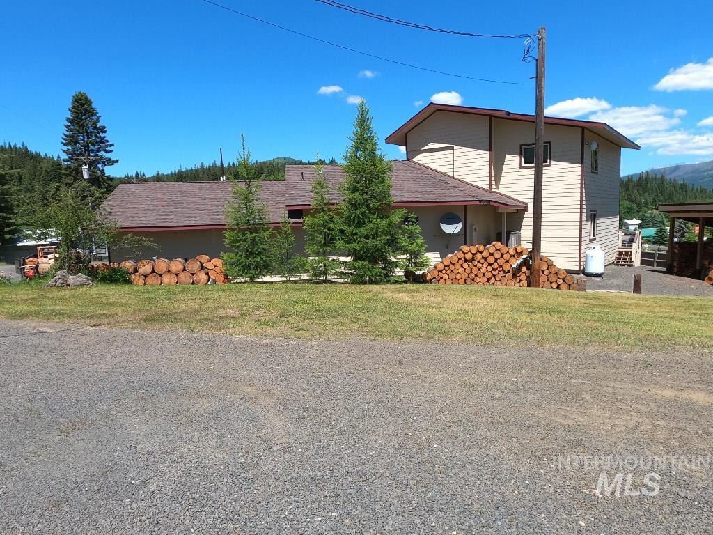 View of side of home featuring a shingled roof and a yard