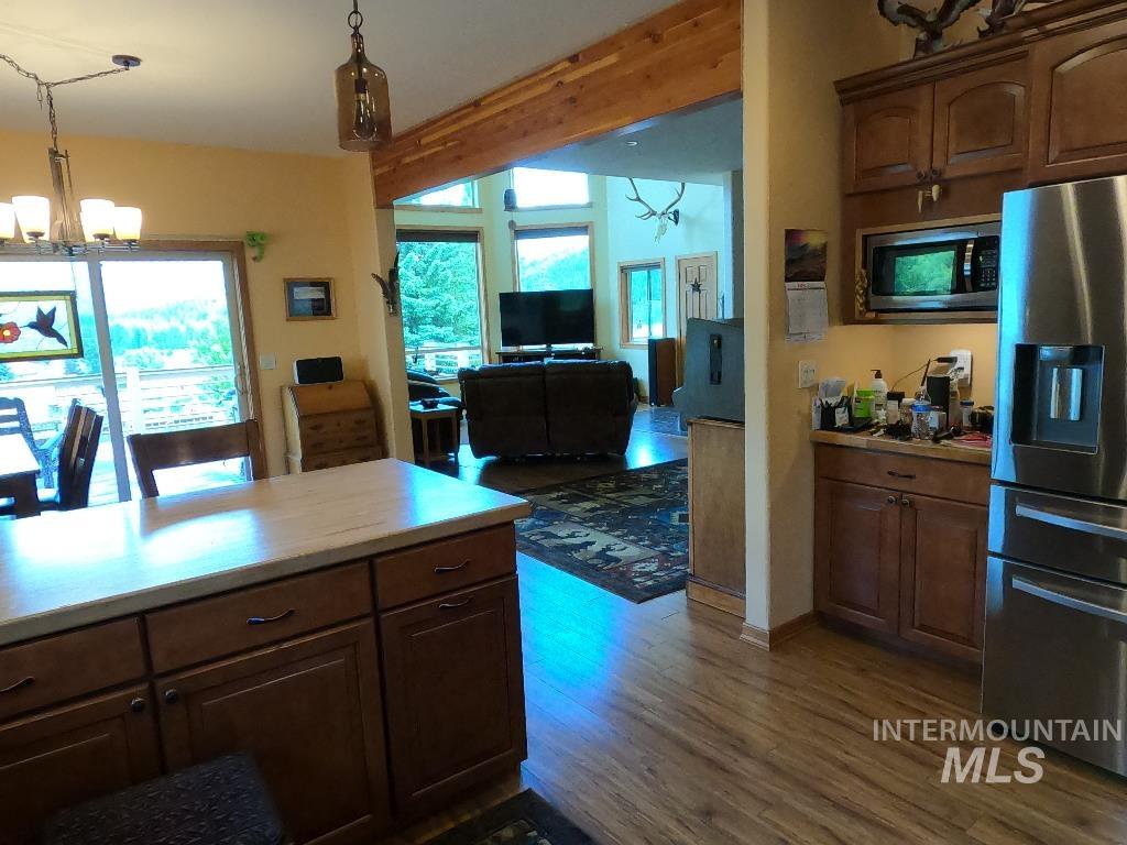 Kitchen featuring a chandelier, appliances with stainless steel finishes, wood finished floors, hanging light fixtures, and open floor plan
