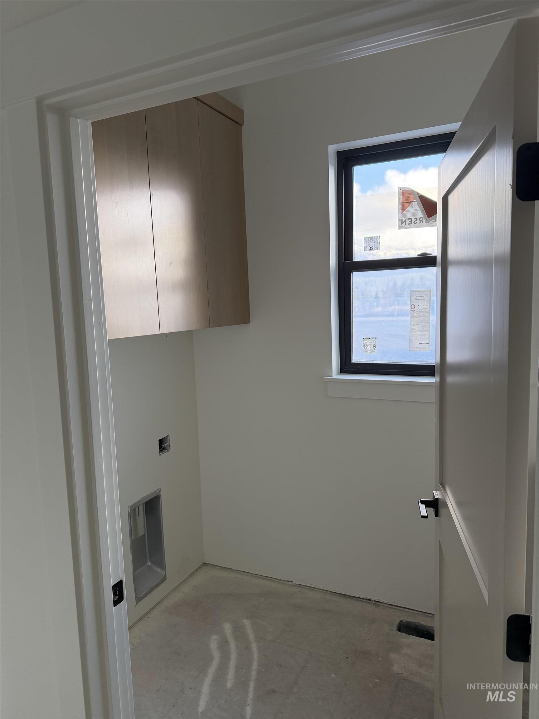 Laundry room featuring concrete flooring and cabinet space