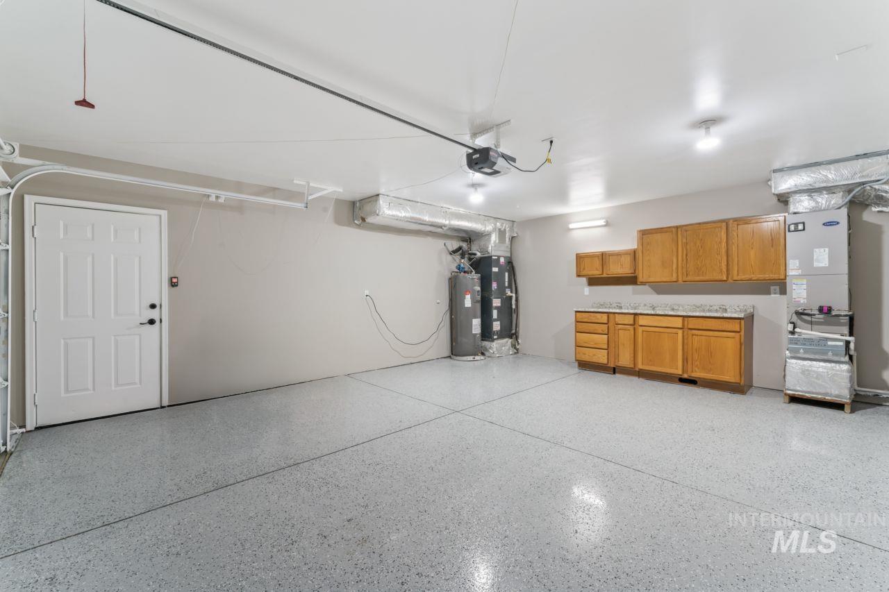 Garage with water heater, heating unit, and a garage door opener