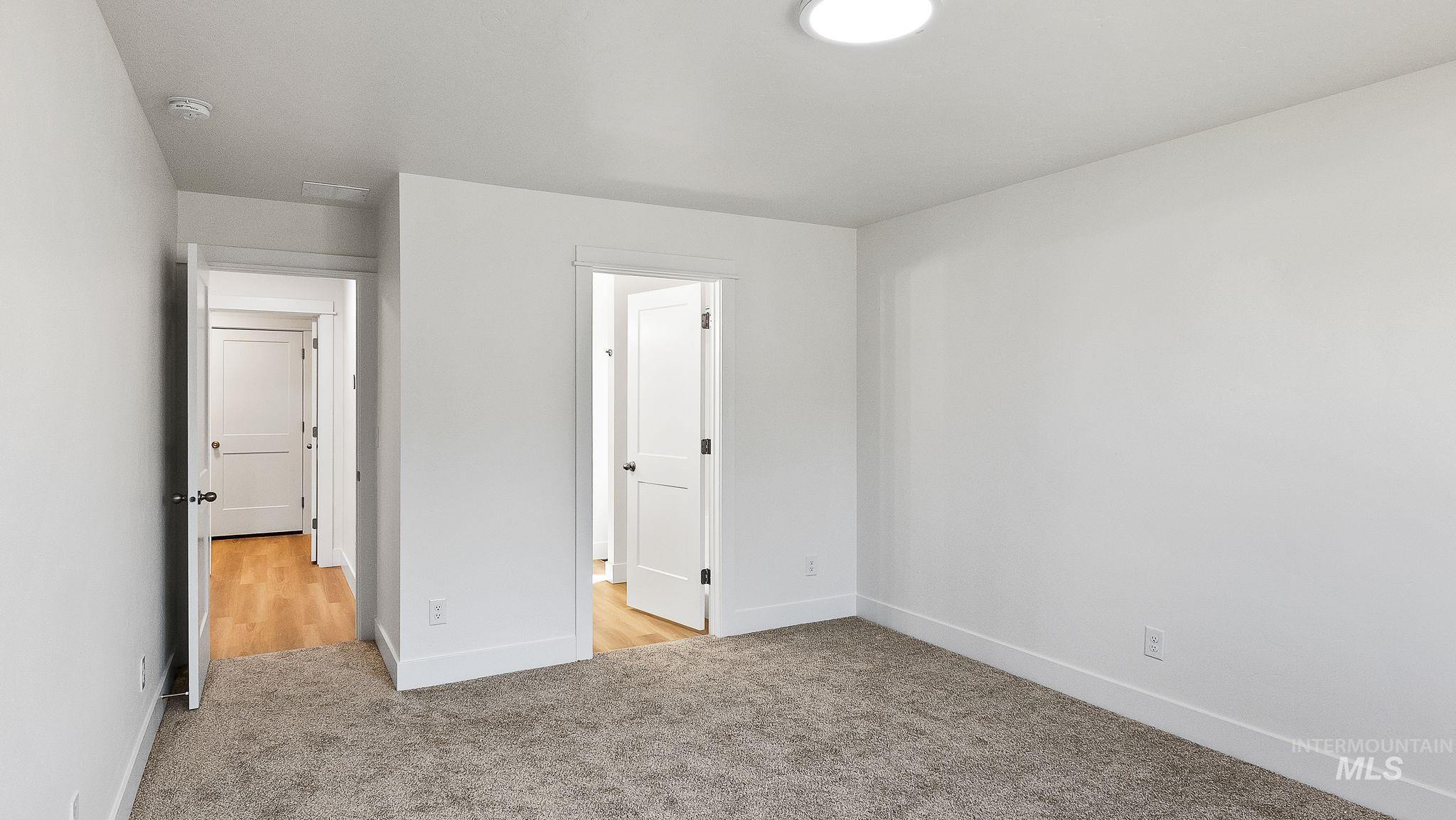 Unfurnished bedroom with light carpet and baseboards