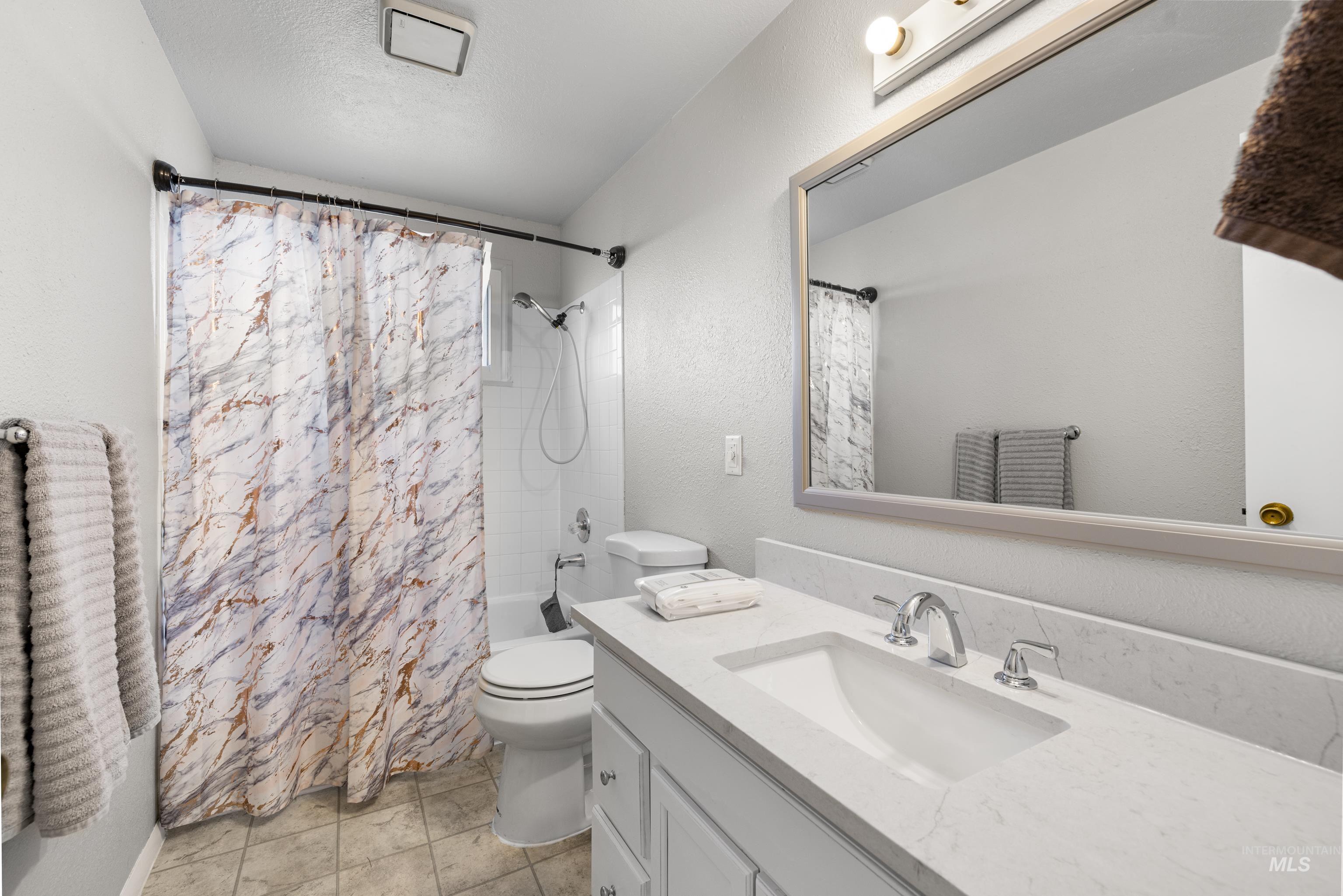 Bathroom with vanity, shower / tub combo with curtain, and tile patterned flooring