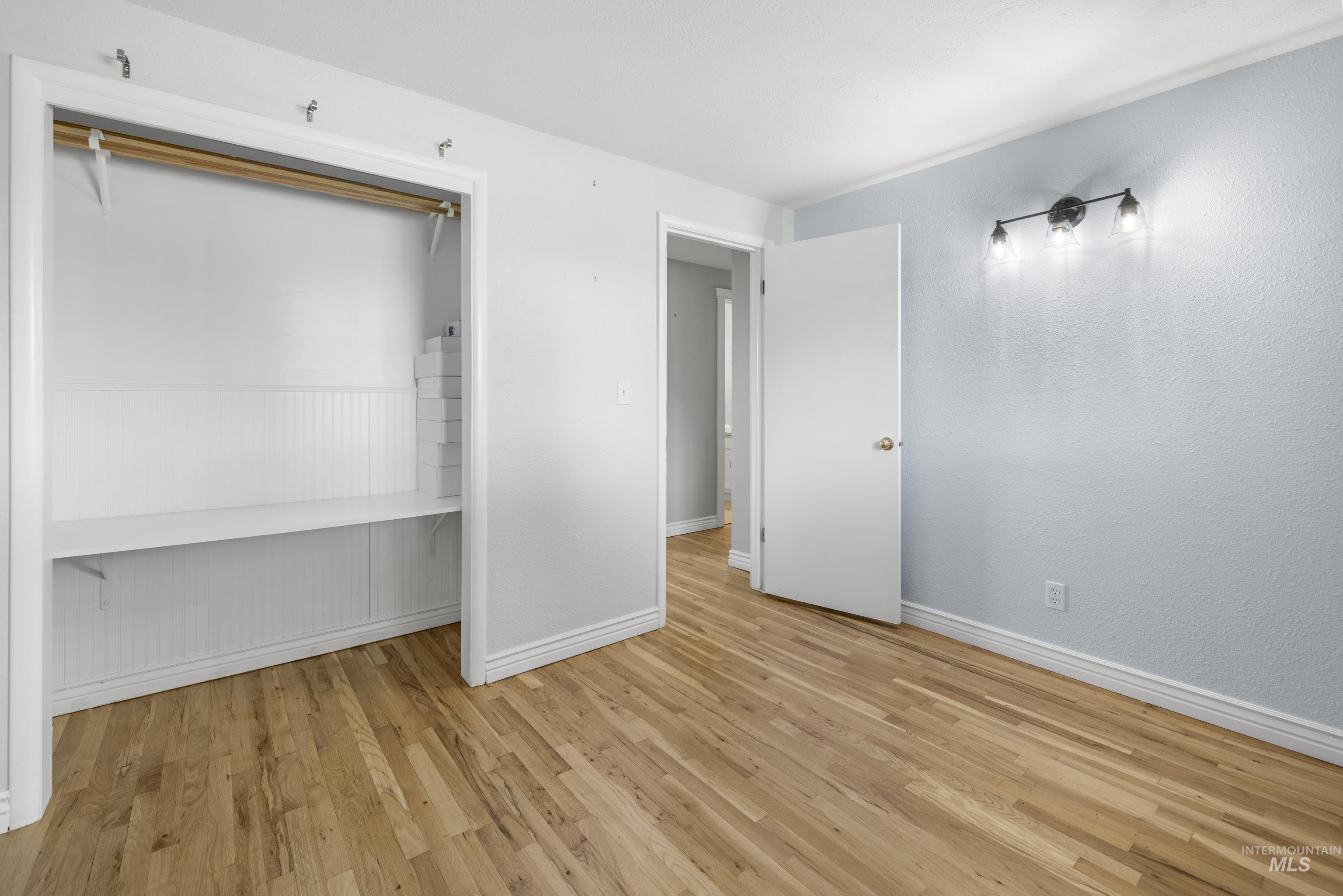 Unfurnished bedroom with wood finished floors and a closet