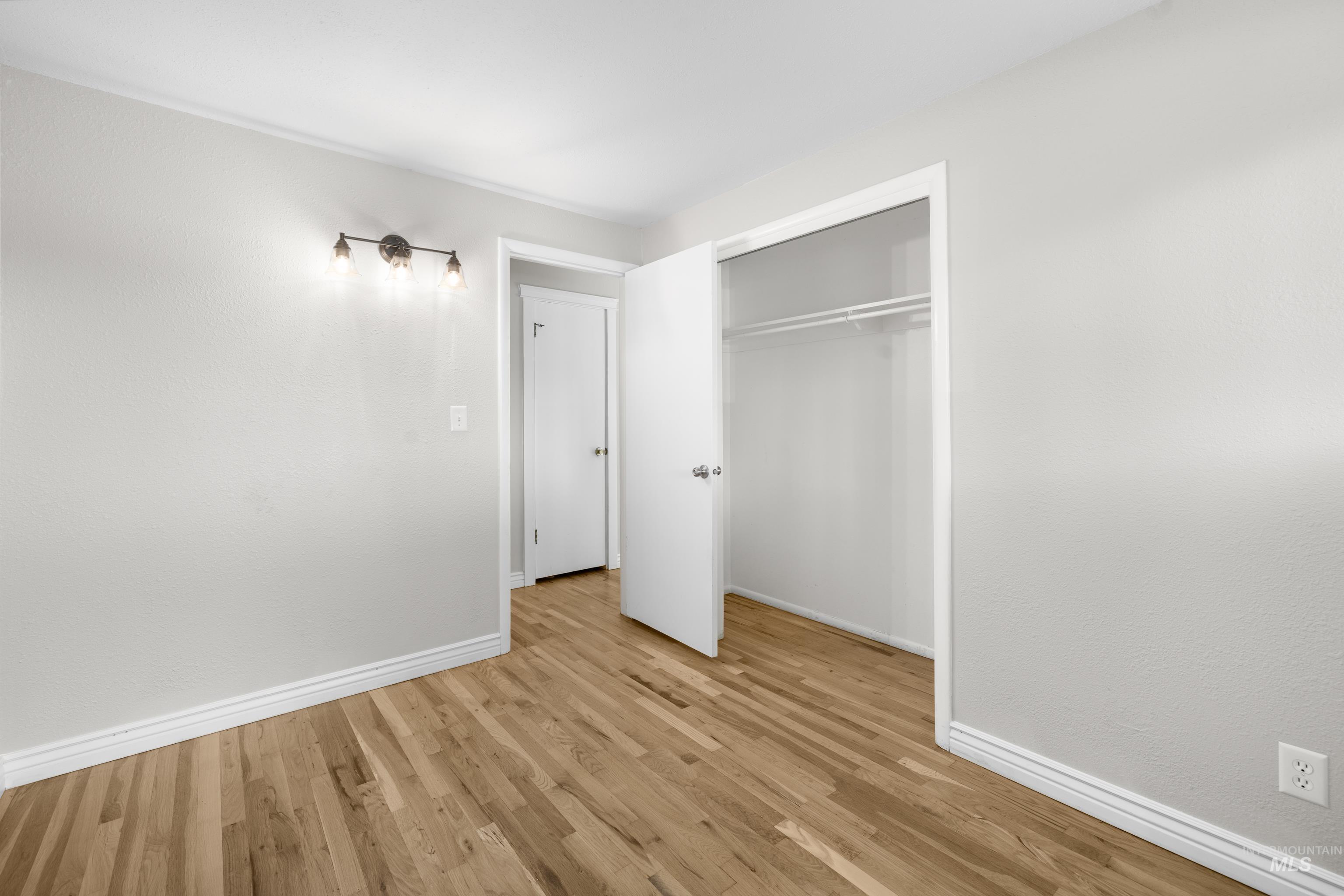 Unfurnished bedroom with light wood-style floors and a closet