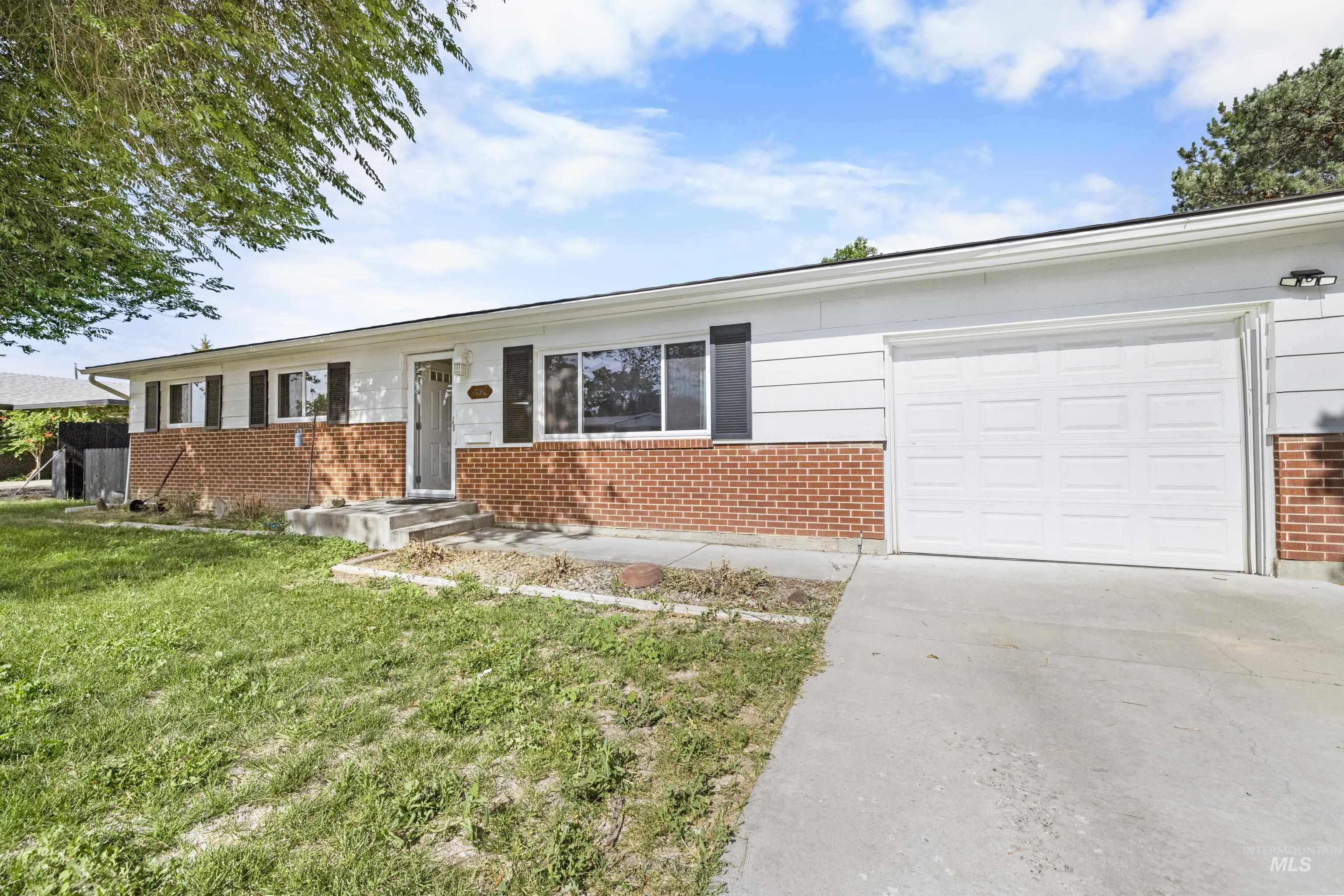 Ranch-style home featuring brick siding, concrete driveway, an attached garage, and a front yard