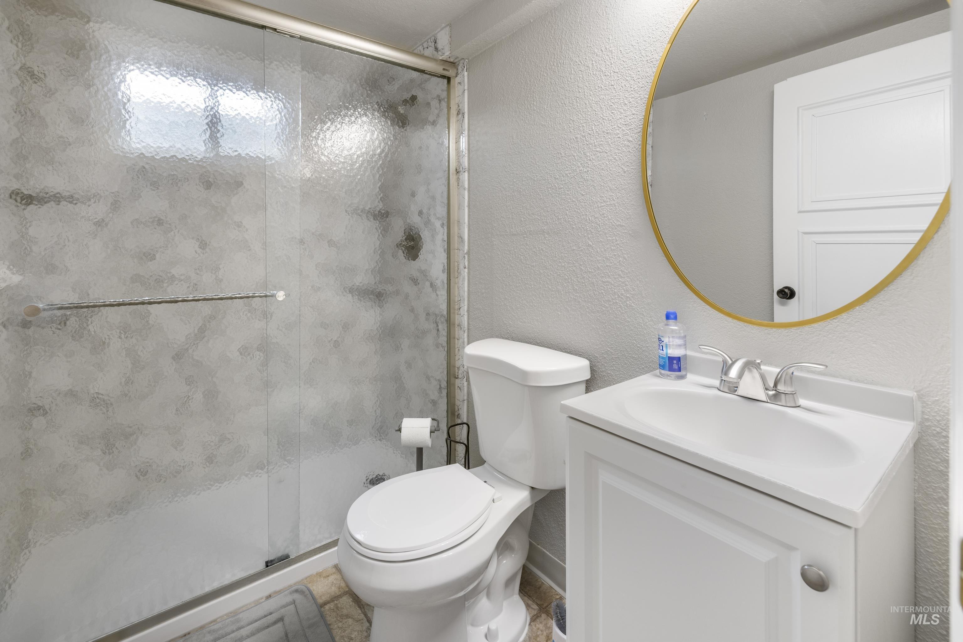 Bathroom featuring vanity, a stall shower, and a textured wall