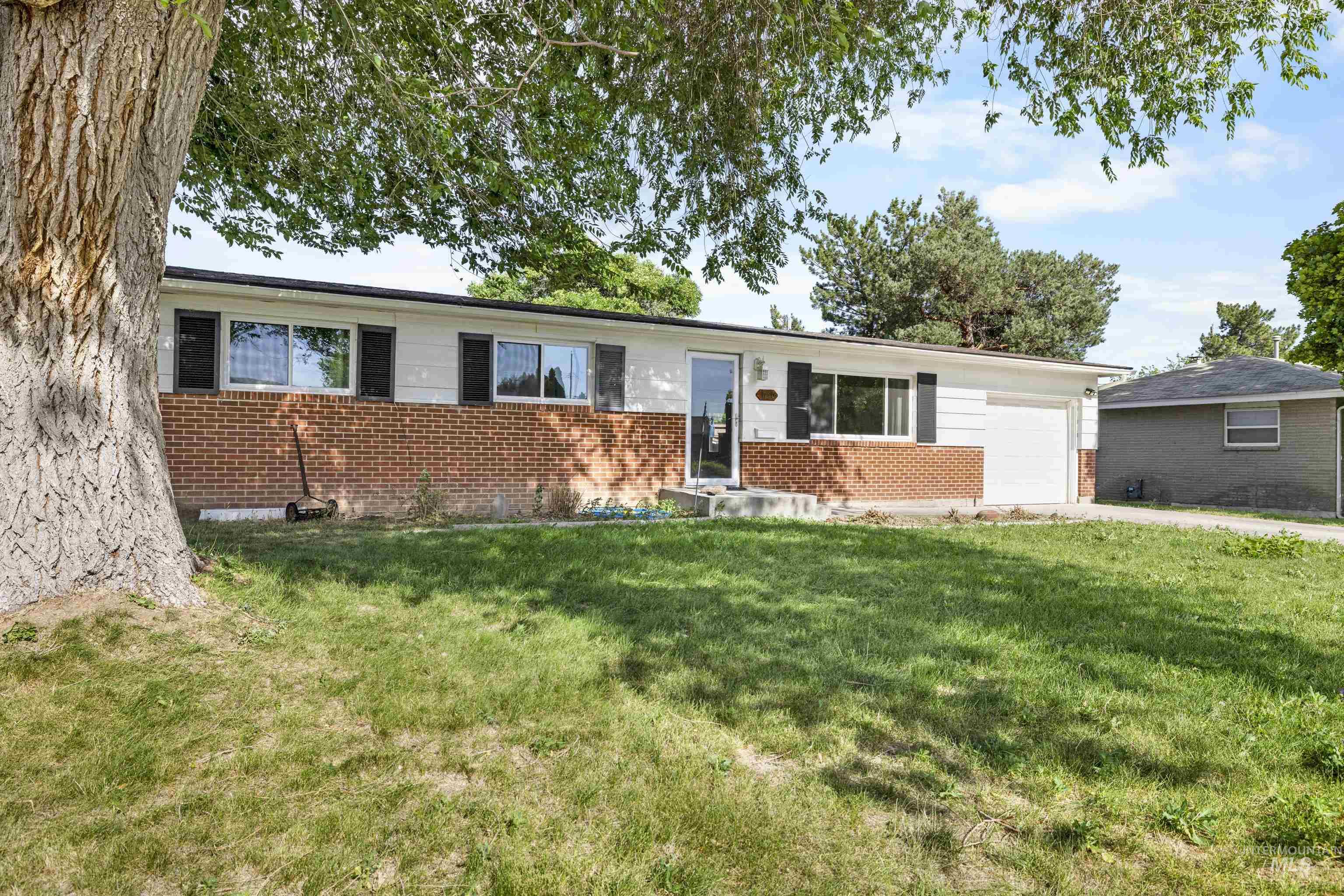 Single story home featuring brick siding, a garage, and a front lawn