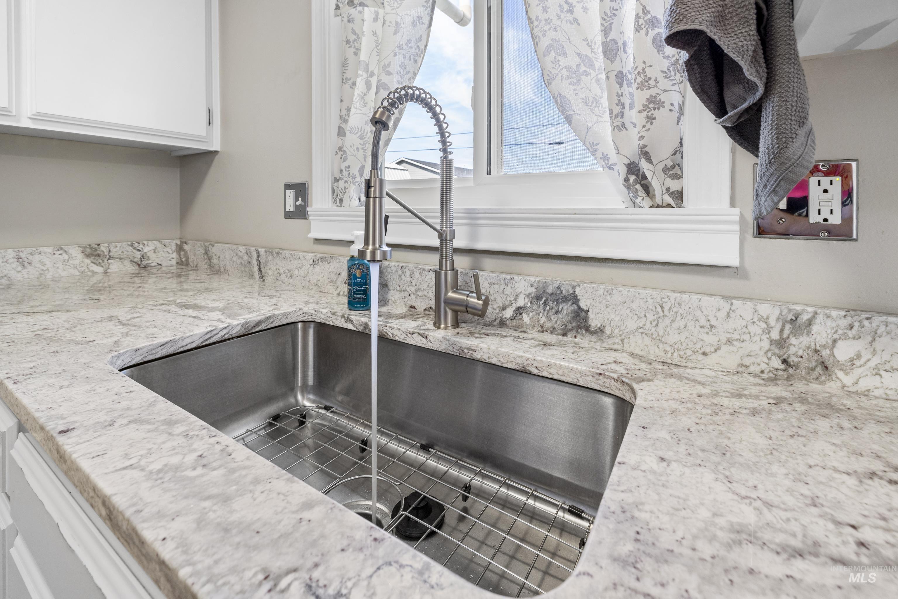 Kitchen view of white cabinetry and light stone countertops