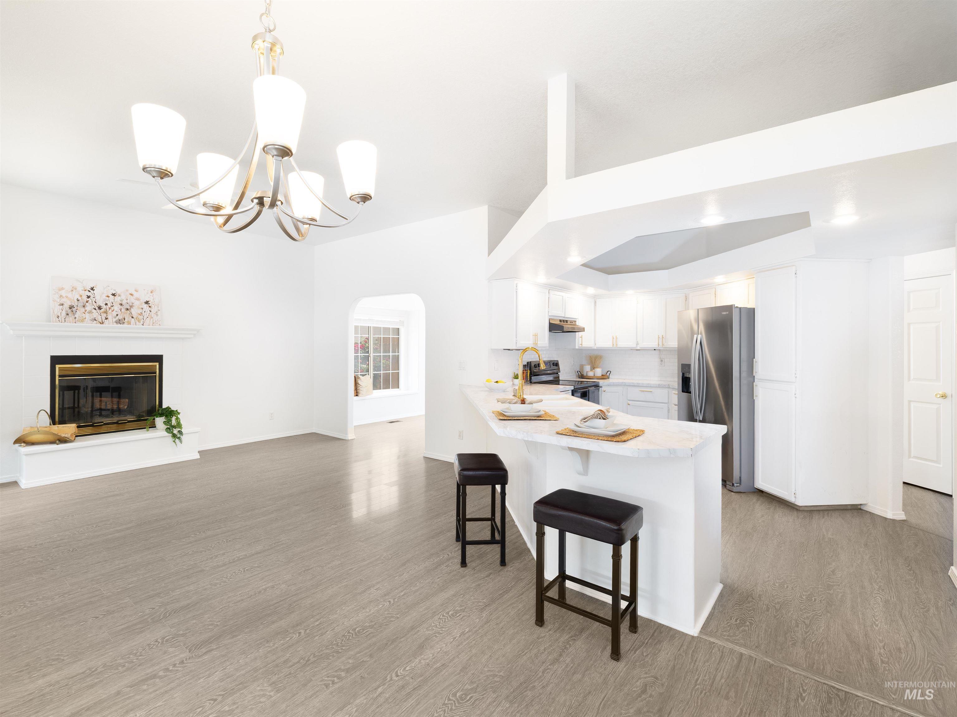 Kitchen with a glass covered fireplace, a peninsula, light countertops, arched walkways, and a breakfast bar