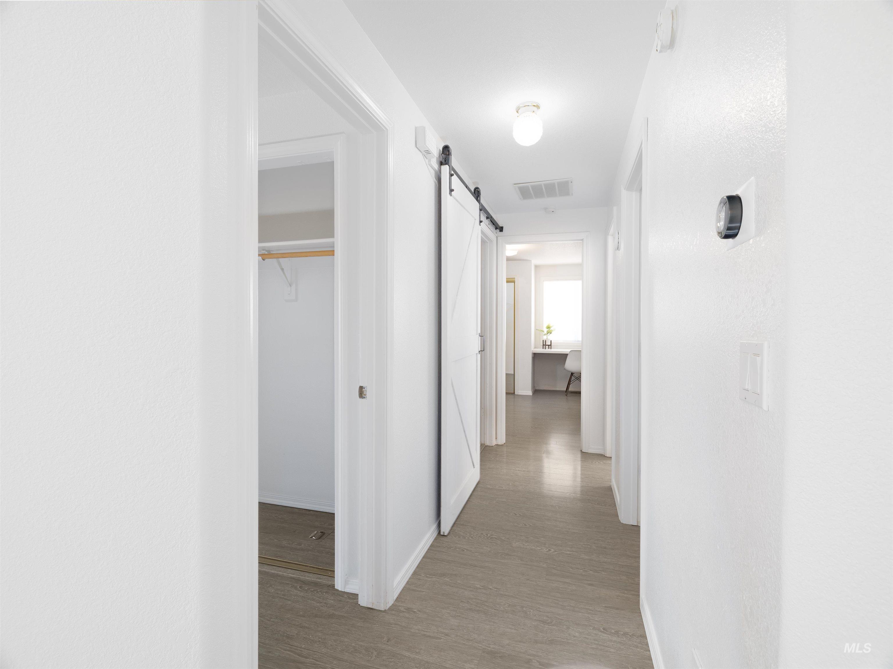 Corridor with wood finished floors and a barn door