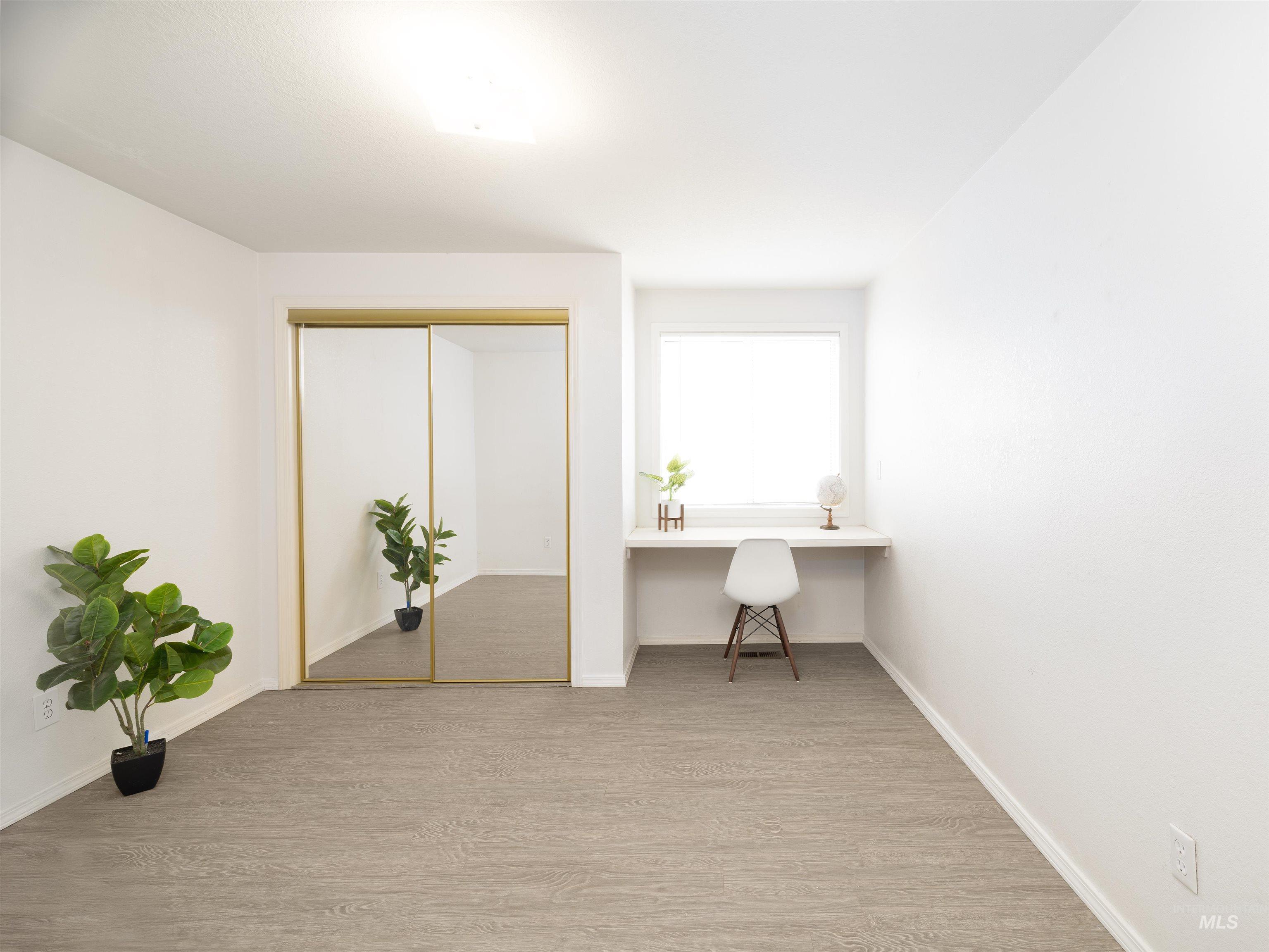Home office with built in study area and light wood-style flooring