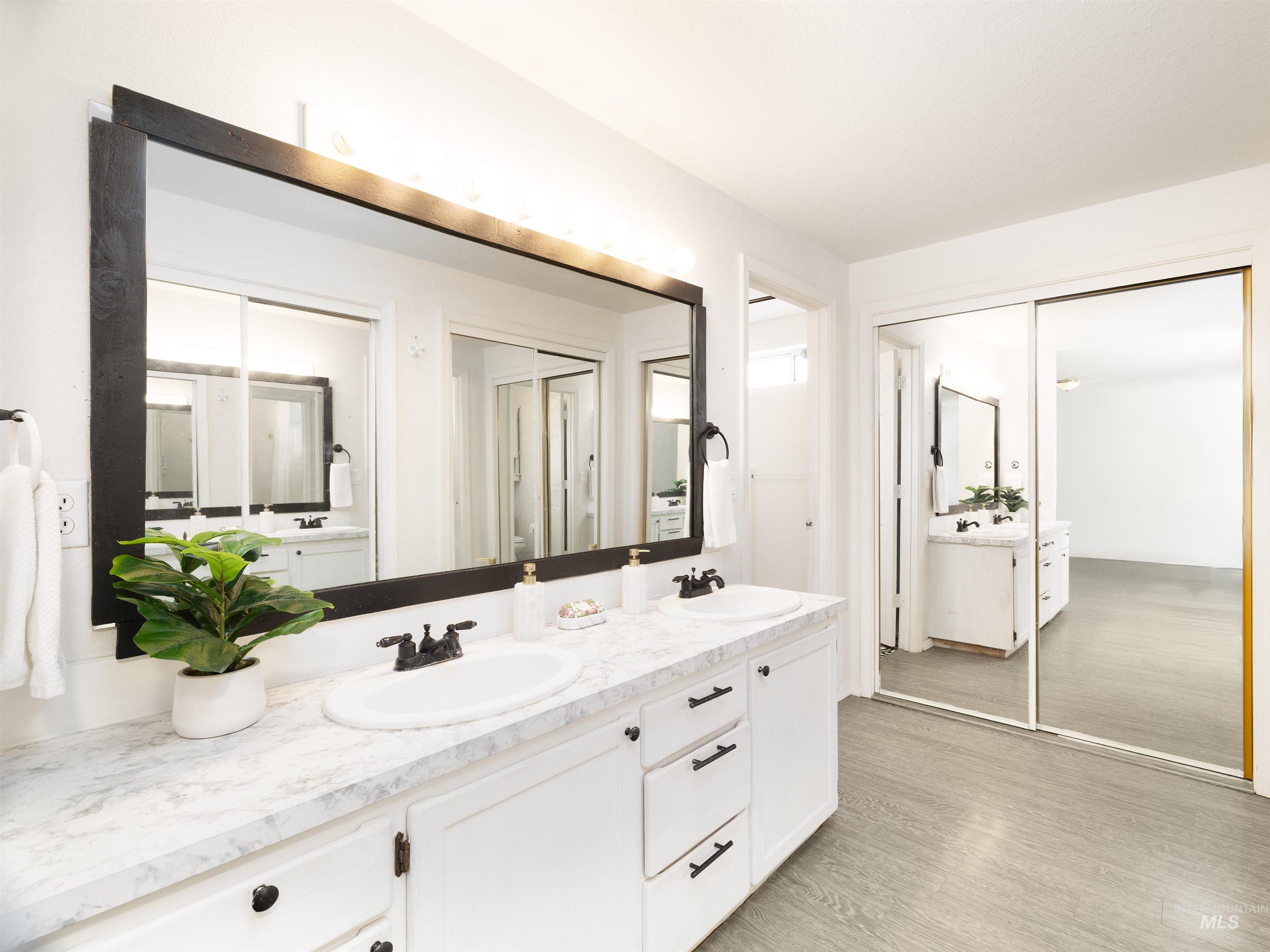 Full bathroom featuring double vanity and wood finished floors