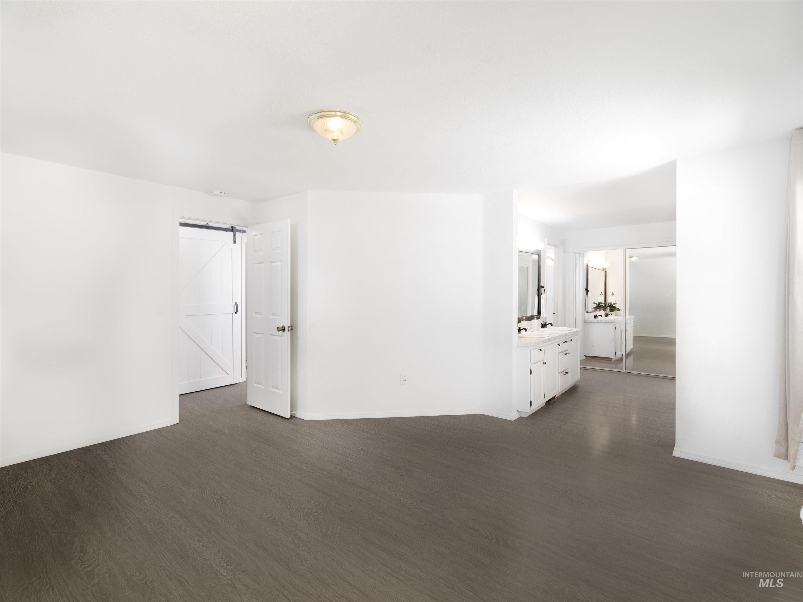 Empty room featuring a barn door and dark wood finished floors