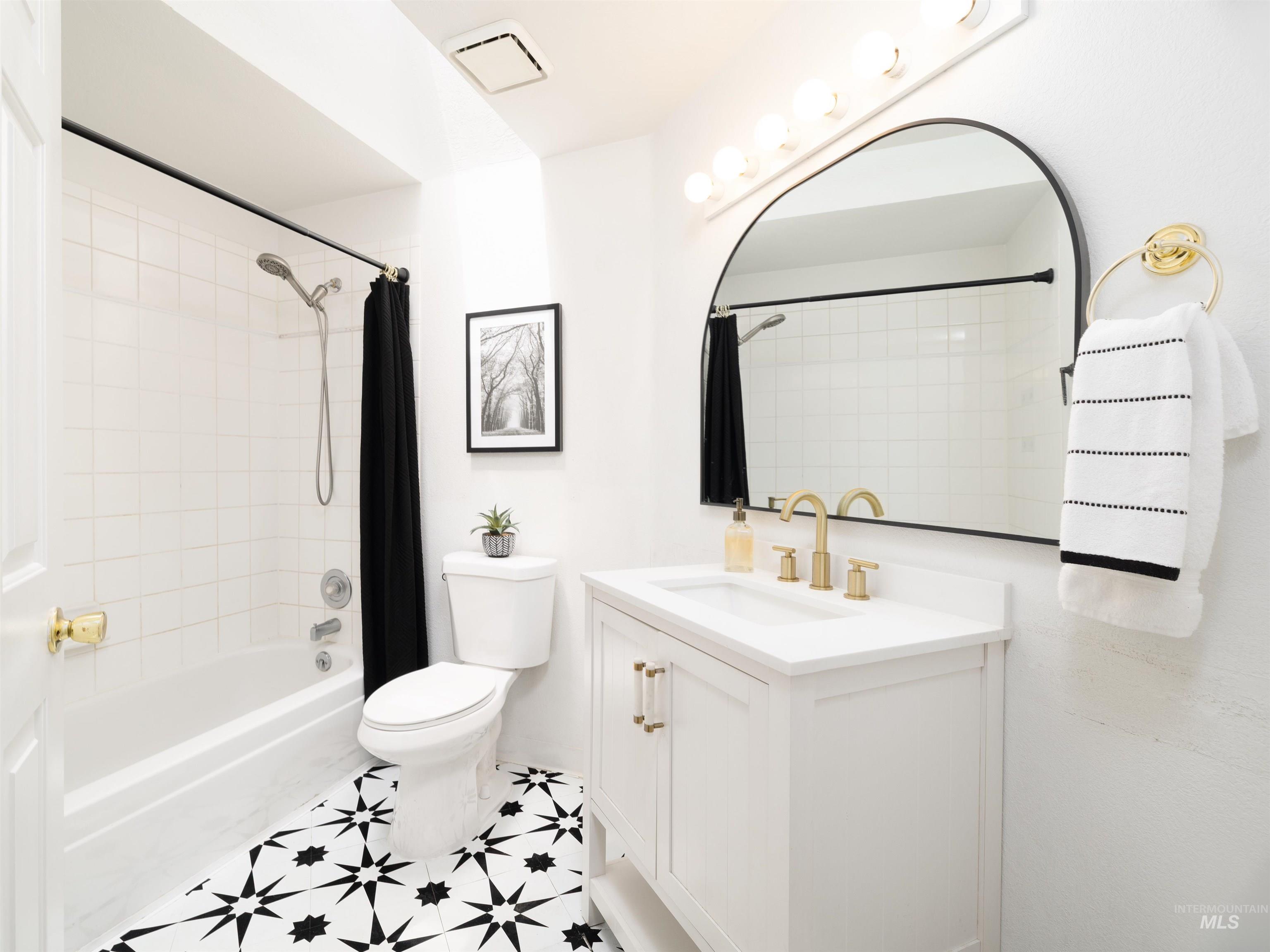 Bathroom featuring vanity and shower / bathtub combination with curtain