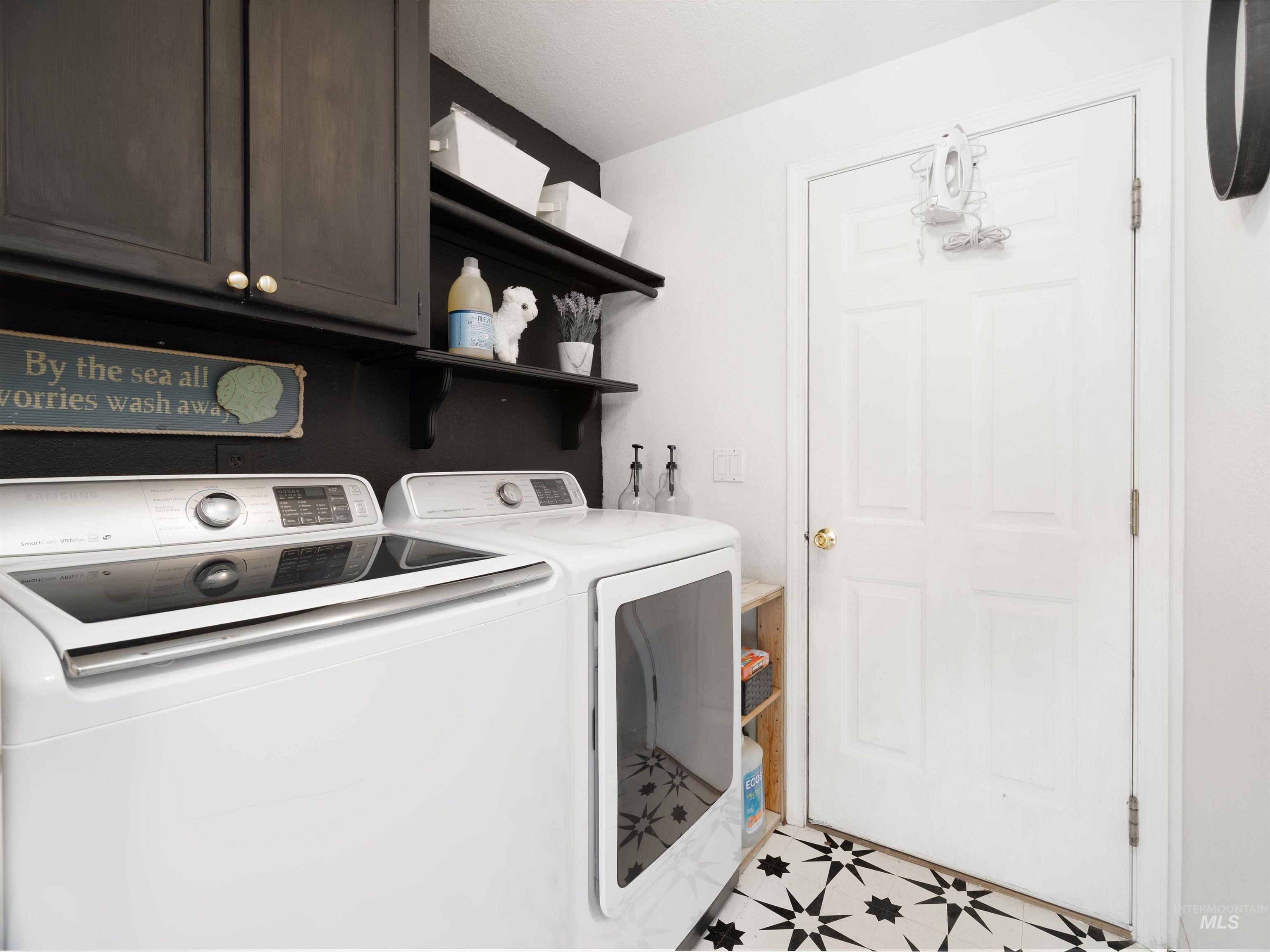 Laundry room featuring independent washer and dryer, cabinet space, and light floors
