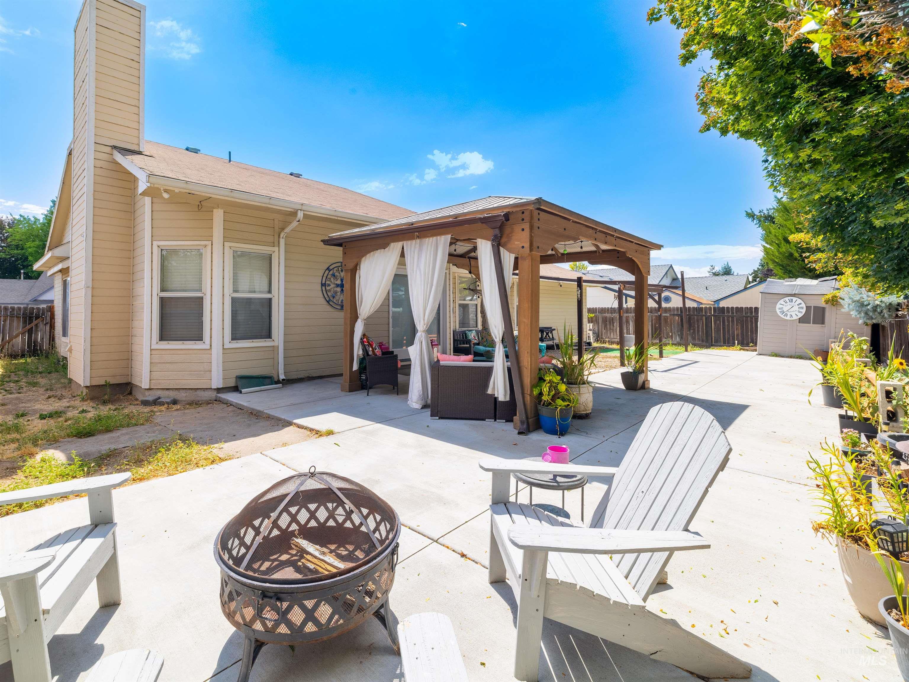 Rear view of property featuring a patio, a gazebo, an outdoor living space with a fire pit, a shed, and a fenced backyard