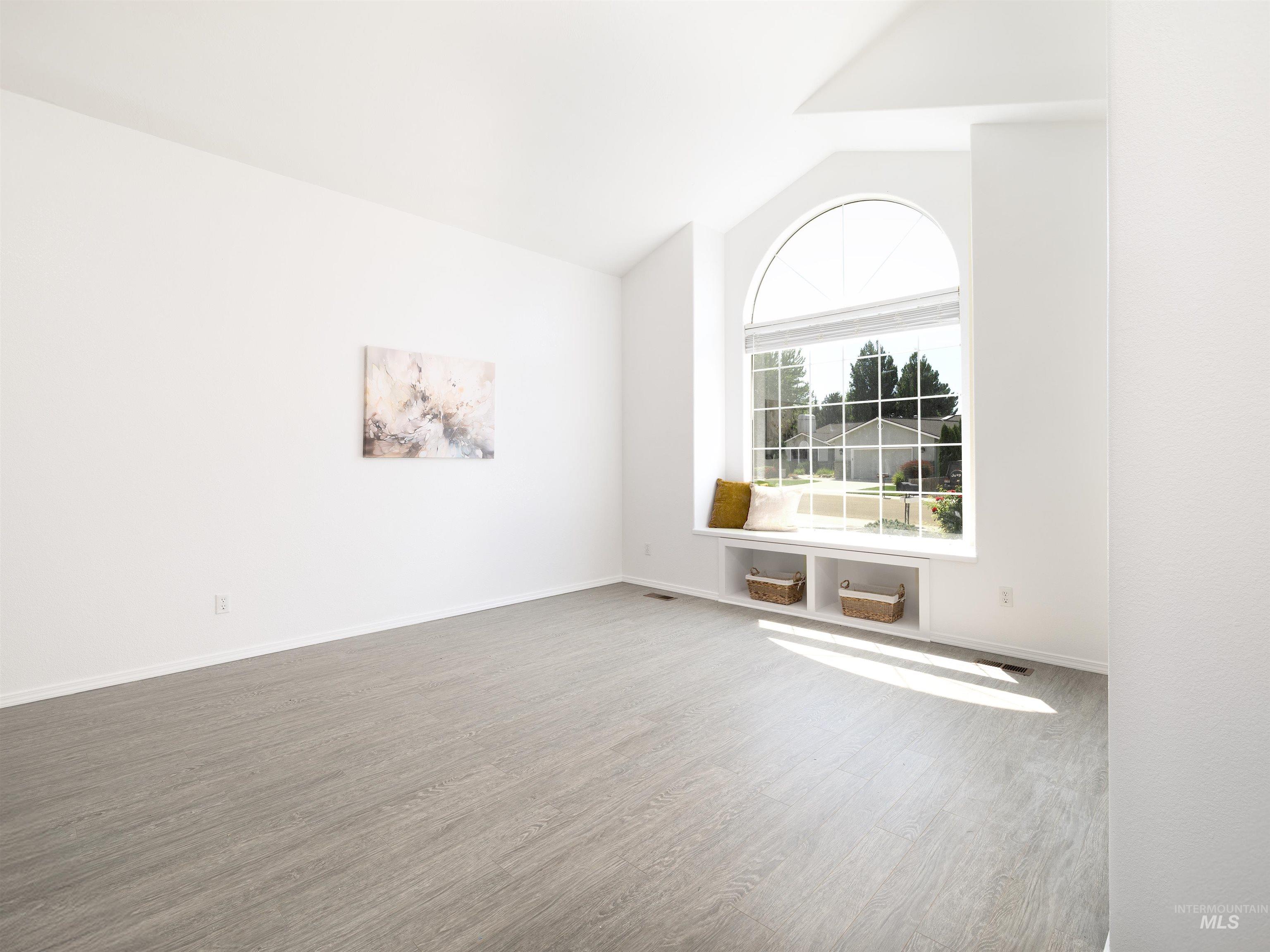 Spare room featuring wood finished floors and vaulted ceiling