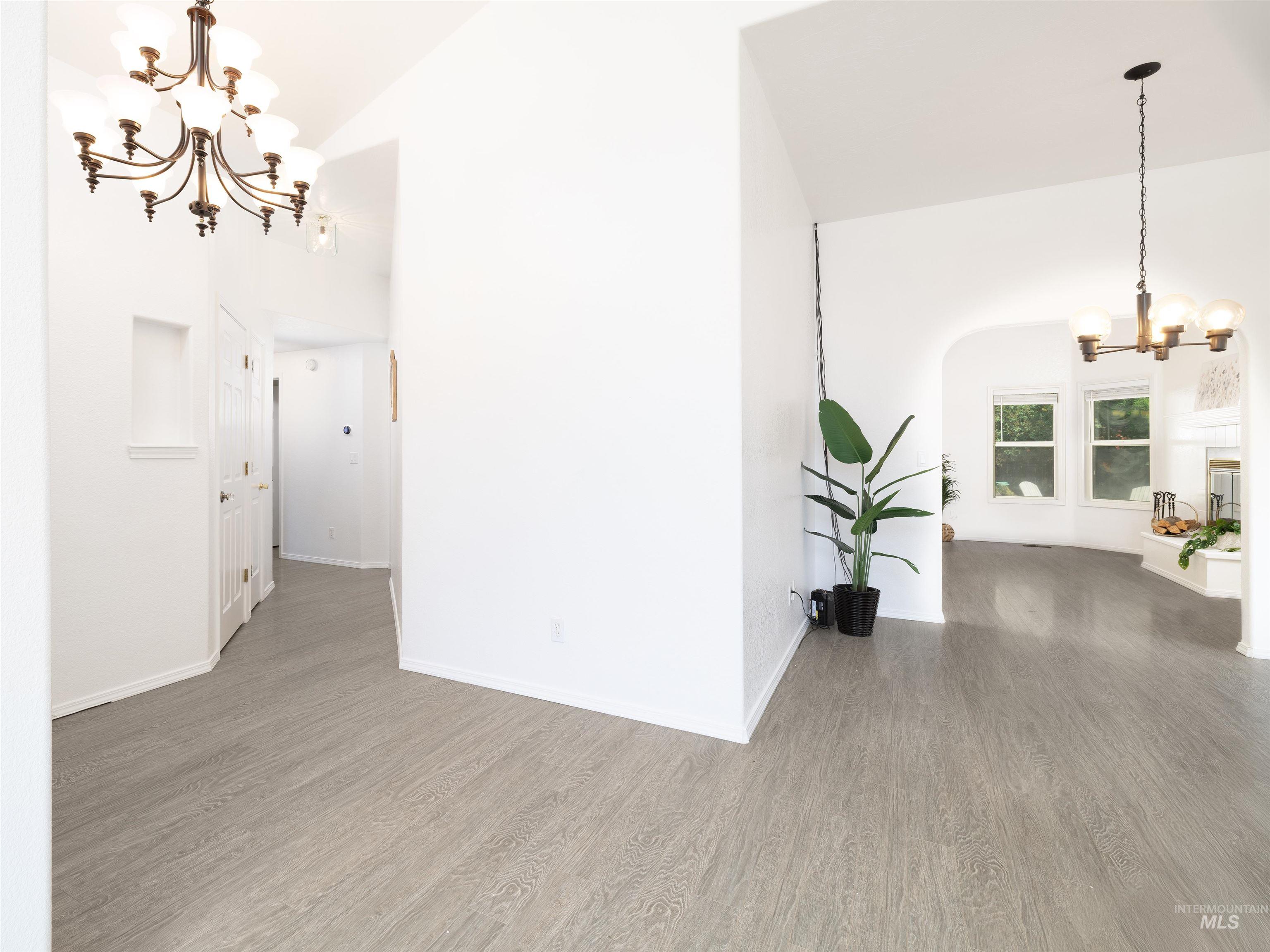 Unfurnished room with a chandelier, wood finished floors, and high vaulted ceiling