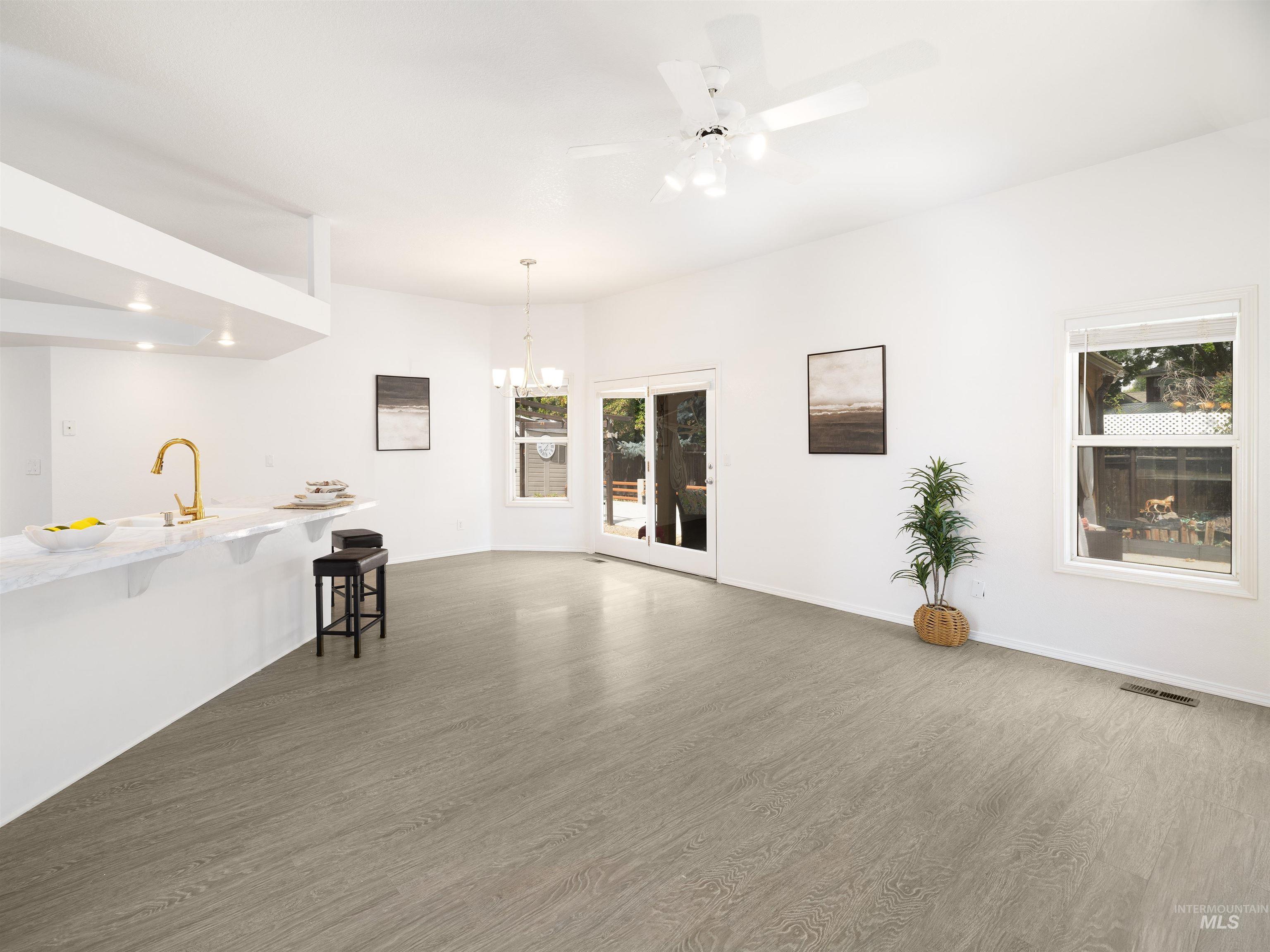 Unfurnished living room featuring dark wood-style floors, ceiling fan, and a chandelier