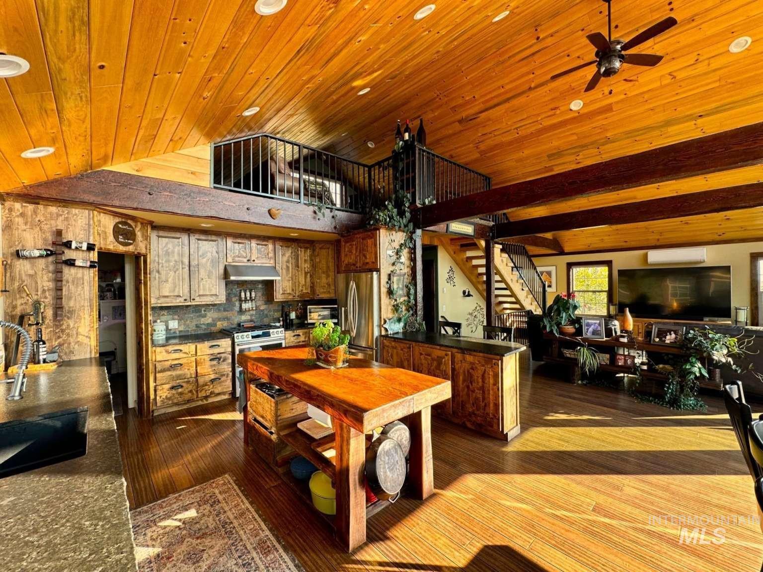 Kitchen featuring dark countertops, appliances with stainless steel finishes, dark wood-style flooring, backsplash, and under cabinet range hood