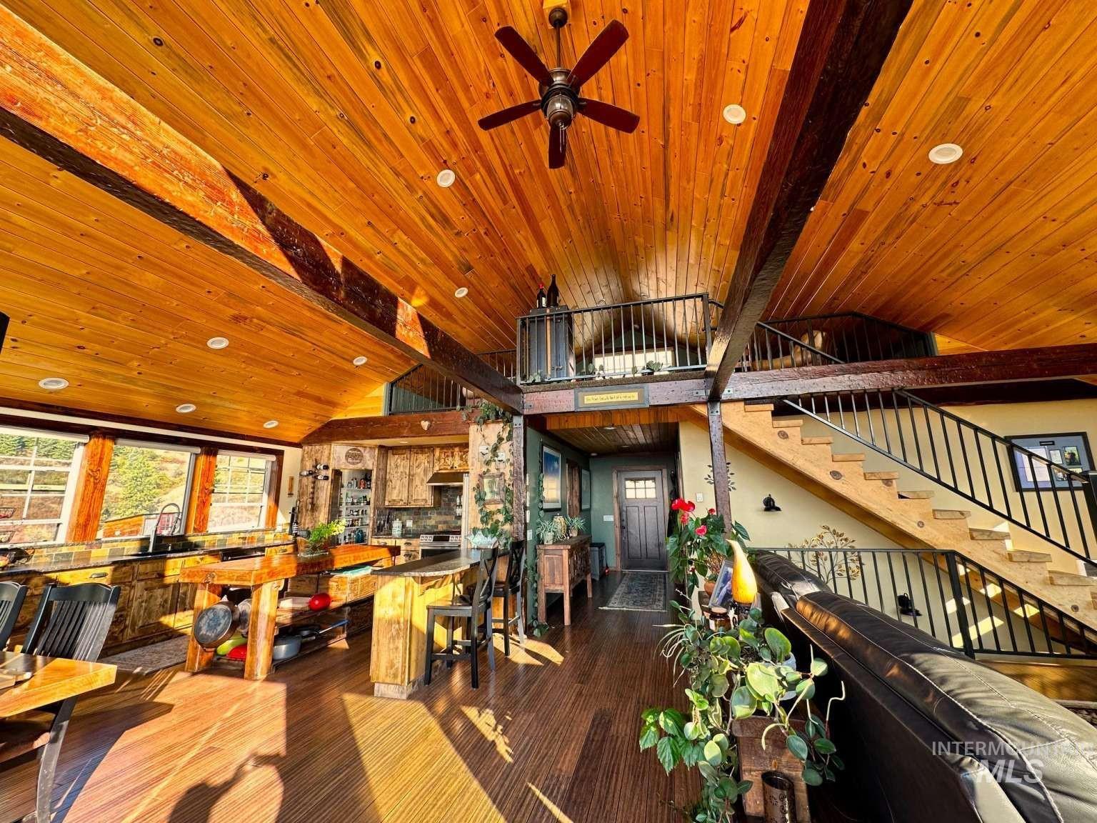 Misc room with dark wood-style floors, stairway, a wooden ceiling with exposed beams, ceiling fan, and high vaulted ceiling