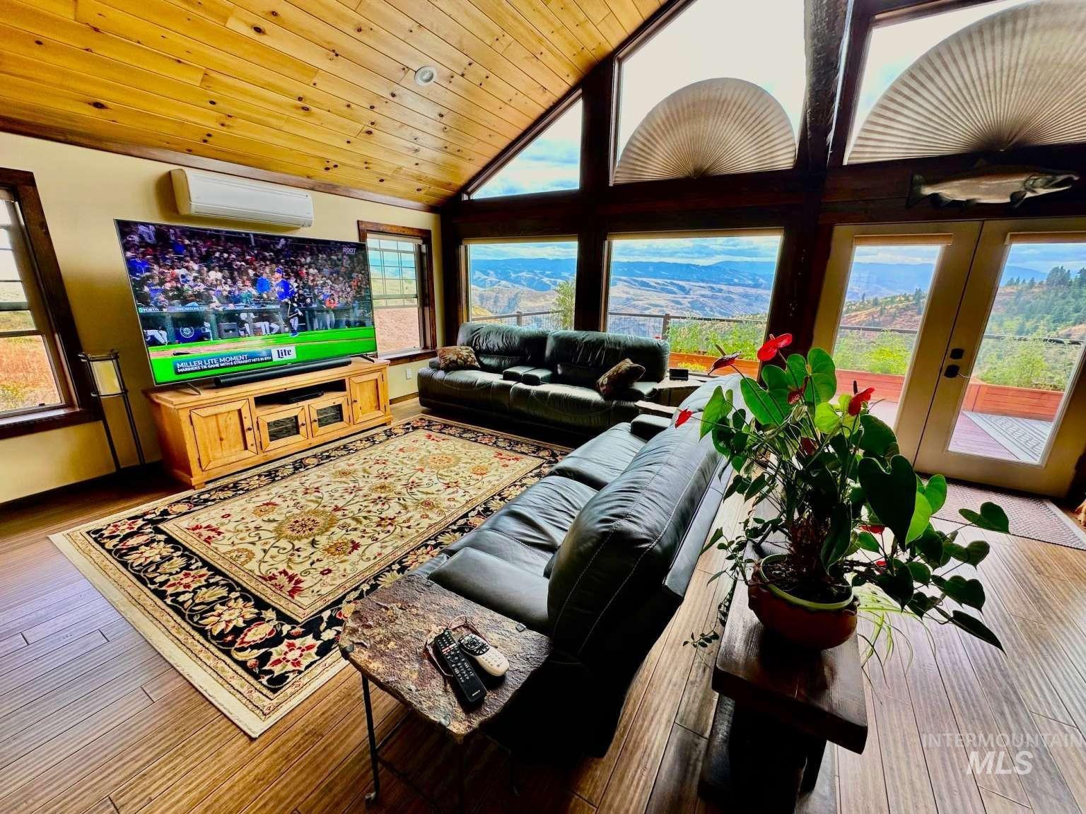 Living room with healthy amount of natural light, hardwood / wood-style flooring, wood ceiling, french doors, and high vaulted ceiling