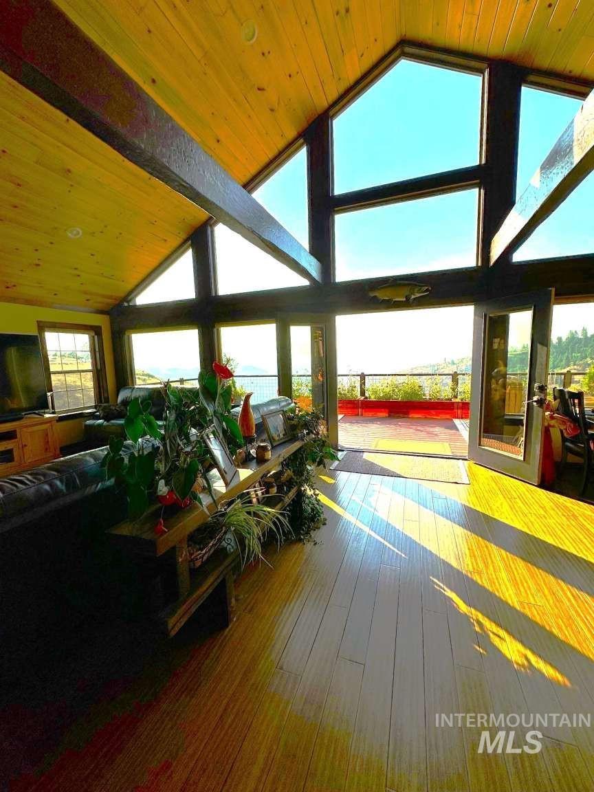 Sunroom with wood ceiling, hardwood / wood-style floors, high vaulted ceiling, and a wall of windows