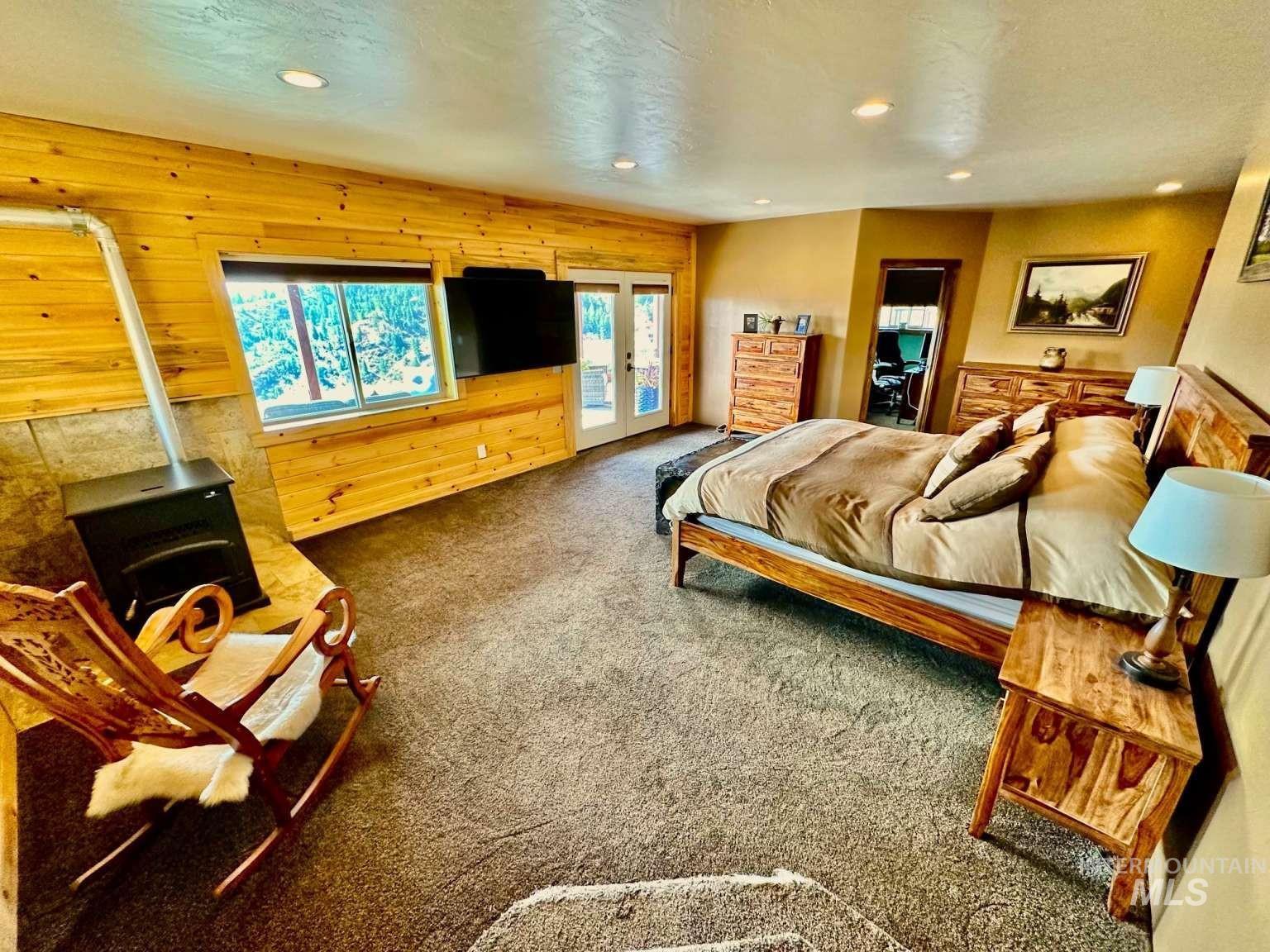 Bedroom with wood walls, access to outside, carpet, a wood stove, and recessed lighting