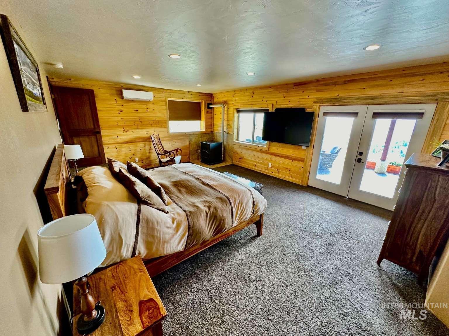 Bedroom featuring carpet floors, wood walls, access to exterior, a textured ceiling, and recessed lighting